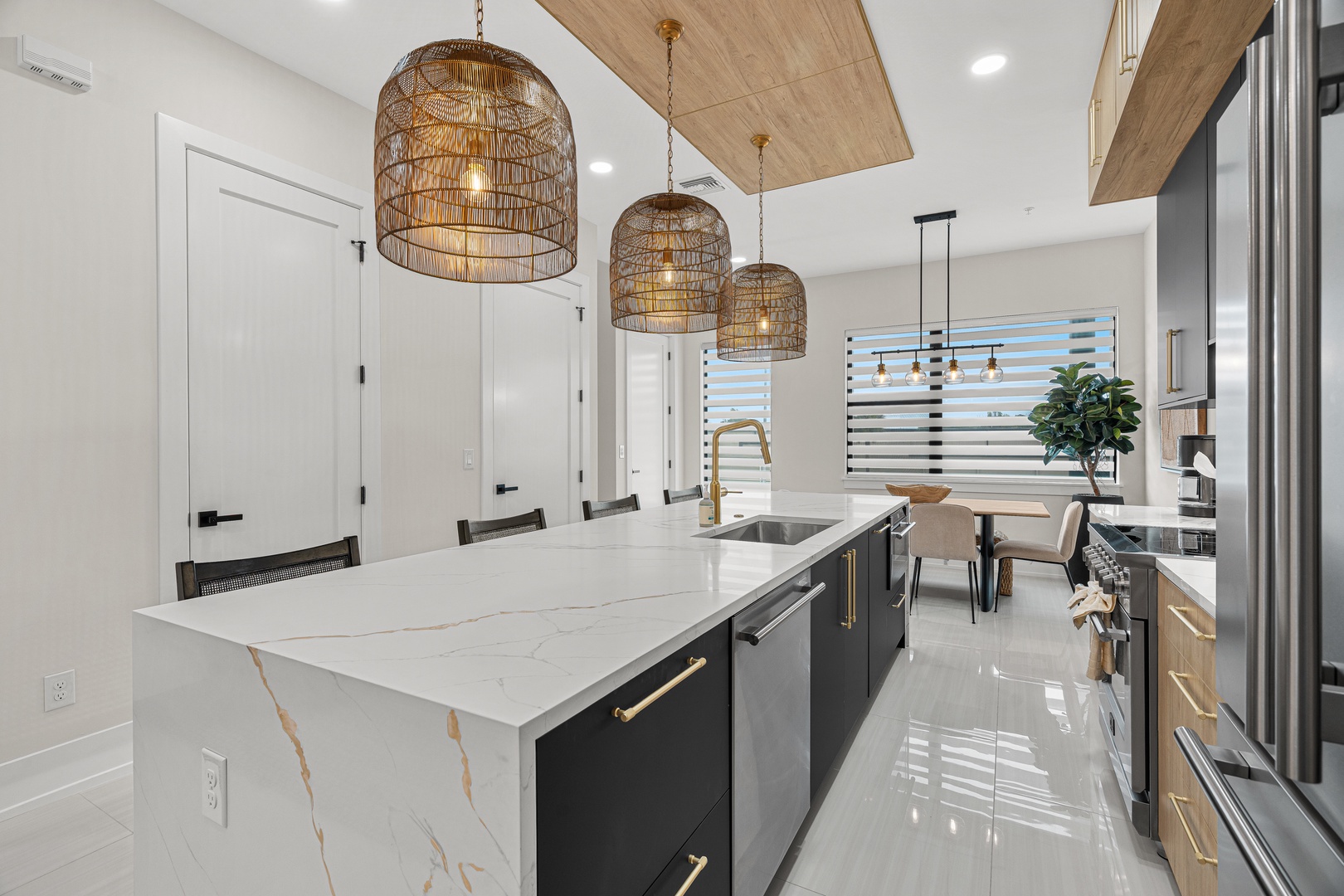 Step into this stunning kitchen where natural light pours in and modern design meets warm textures. The elegant woven pendant lights and marble island create a perfect gathering spot for your vacation meals.