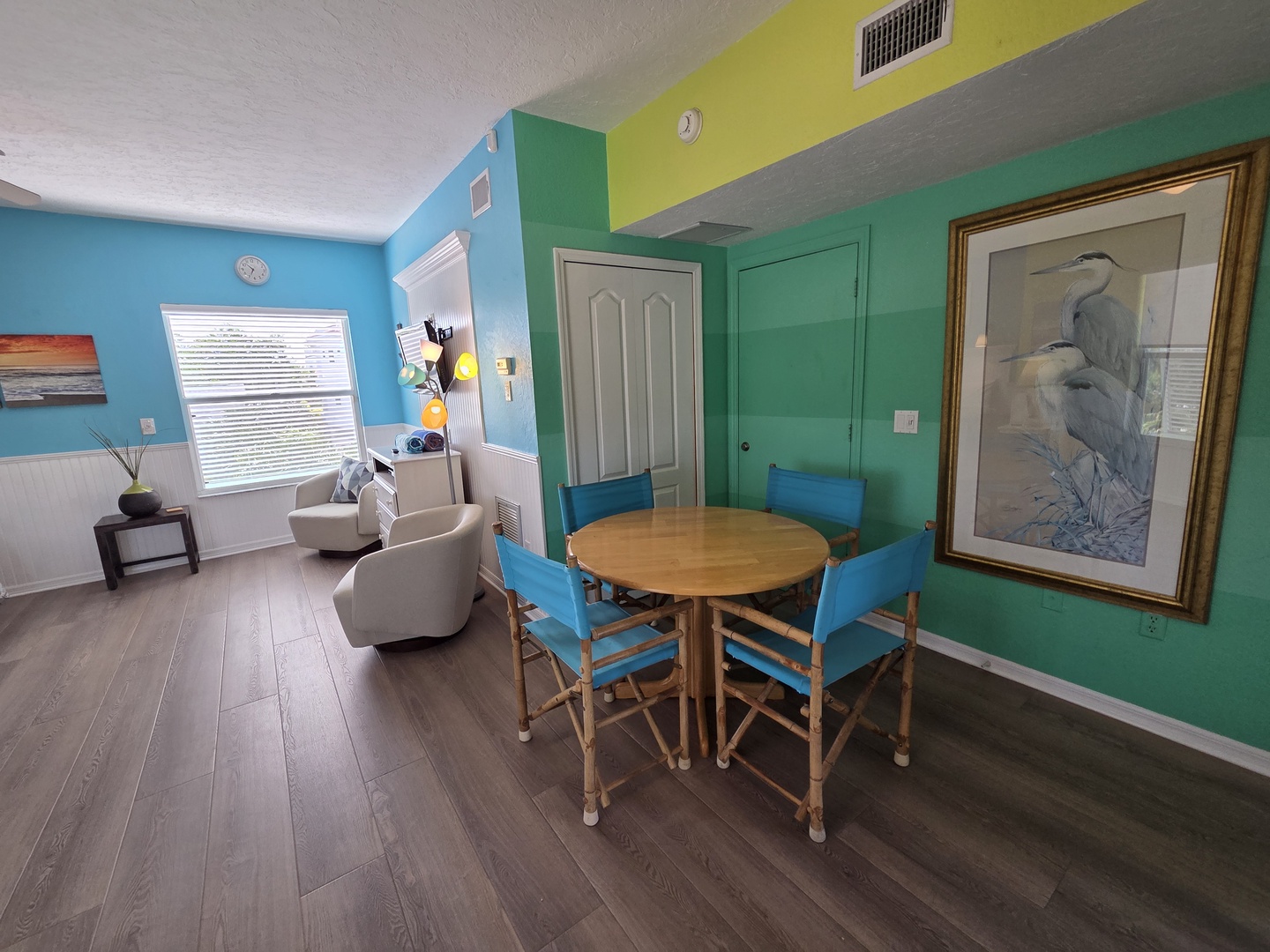Step into your bright coastal retreat, where cheerful blue and teal walls welcome you to a space designed for relaxed beach living. Natural light pours in as you gather for meals at the dining table or unwind in the cozy seating area.