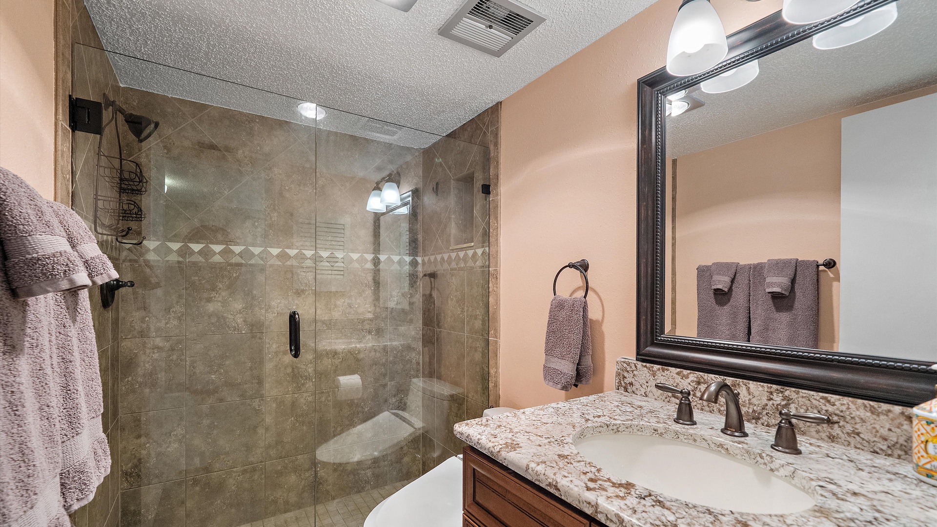 Unwind in your elegant bathroom featuring a spacious glass shower, granite countertops, and plush towels for ultimate comfort.