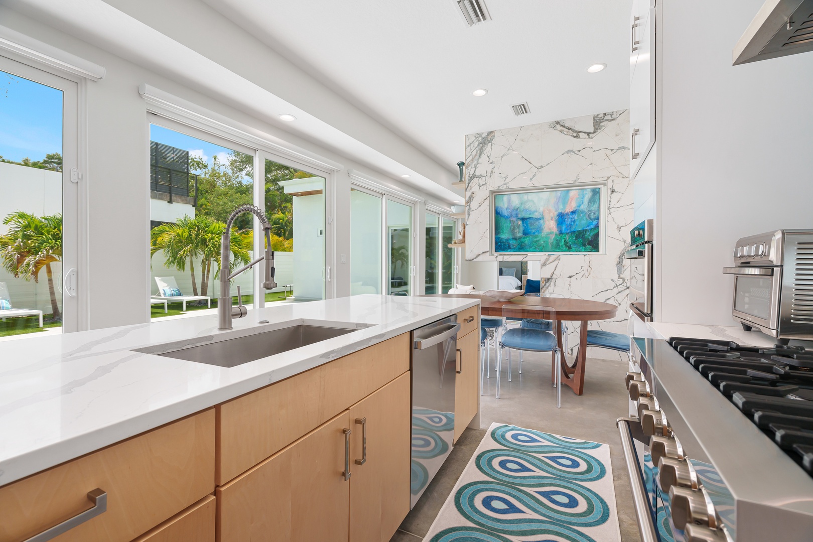 Your dream vacation kitchen: bright, modern, and flooded with natural light. Cook with a view of lush greenery, unwind at the stylish dining table, and feel right at home in this sleek space.