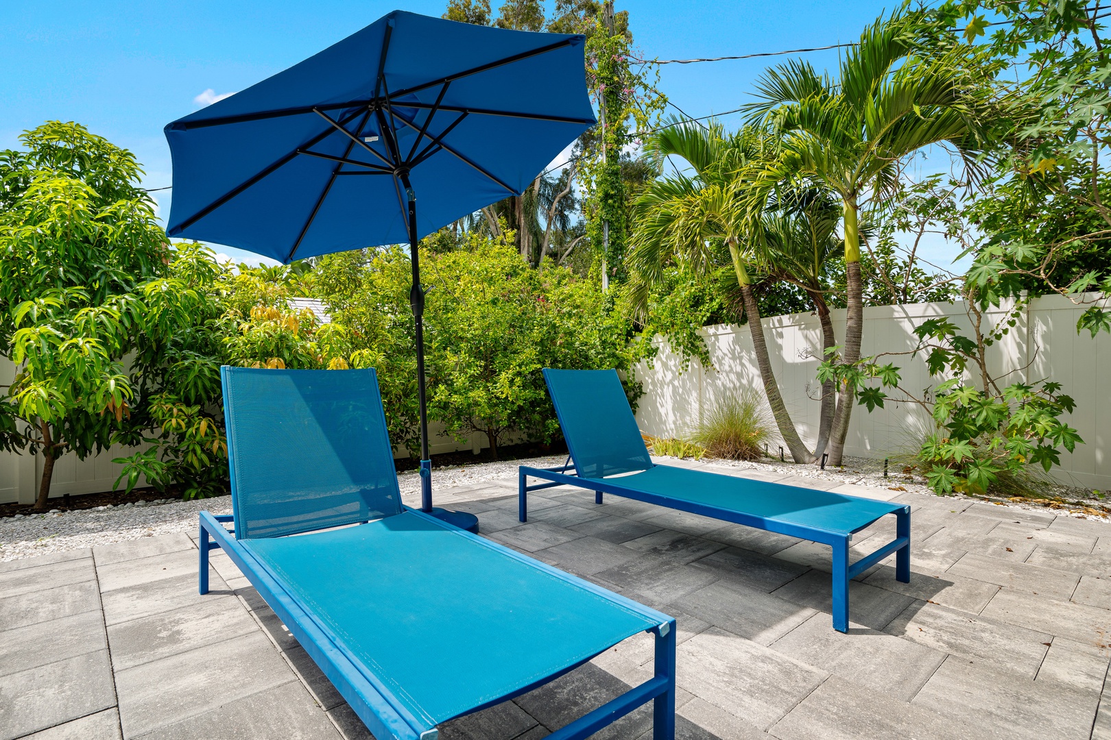 Stretch out under the shade and let tropical breezes wash over you in your private patio oasis, where vivid blue loungers await beneath swaying palms and lush greenery.