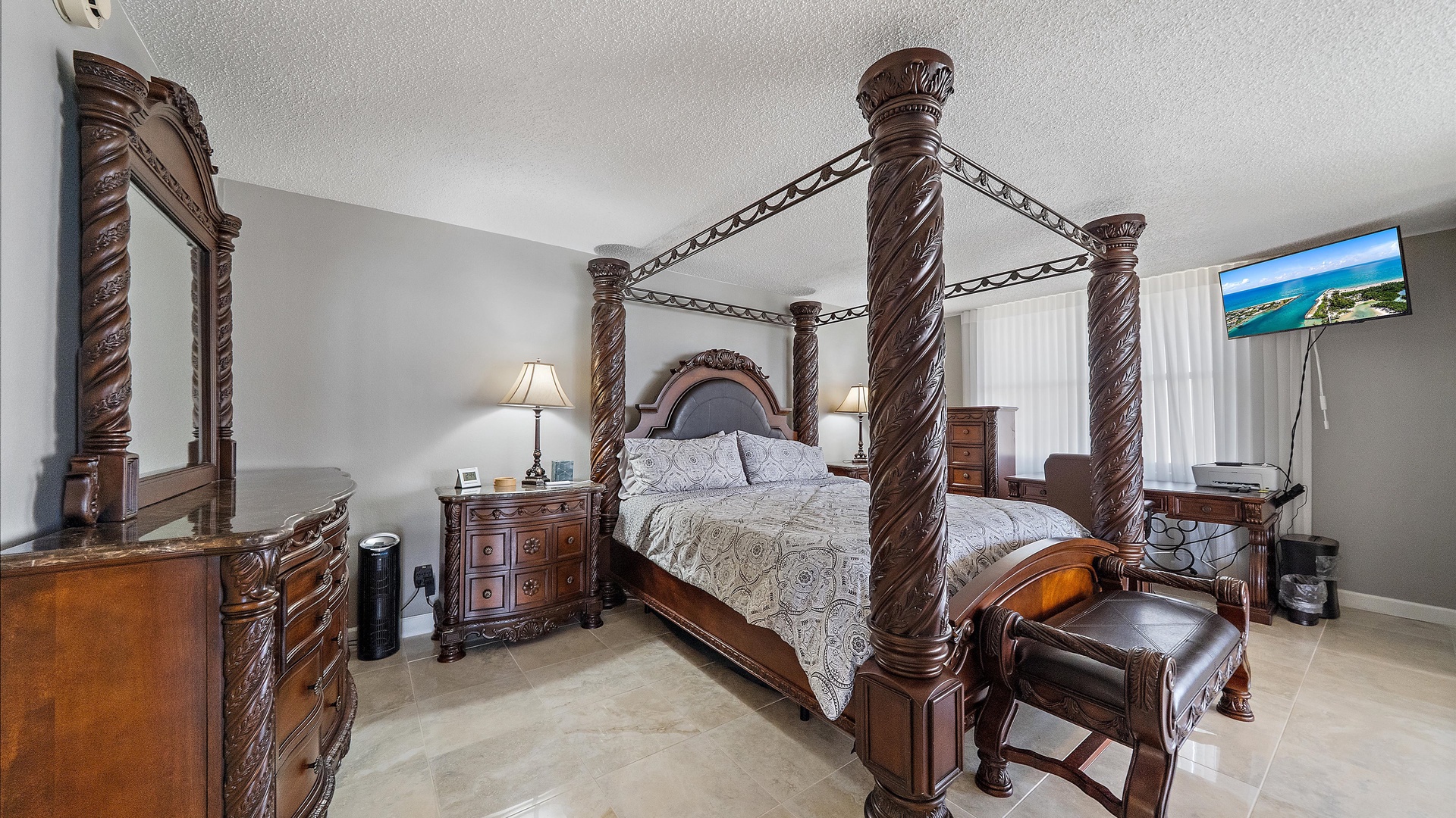 Rest like royalty in this elegant bedroom featuring an ornate four-poster bed with matching carved furnishings and coastal views.