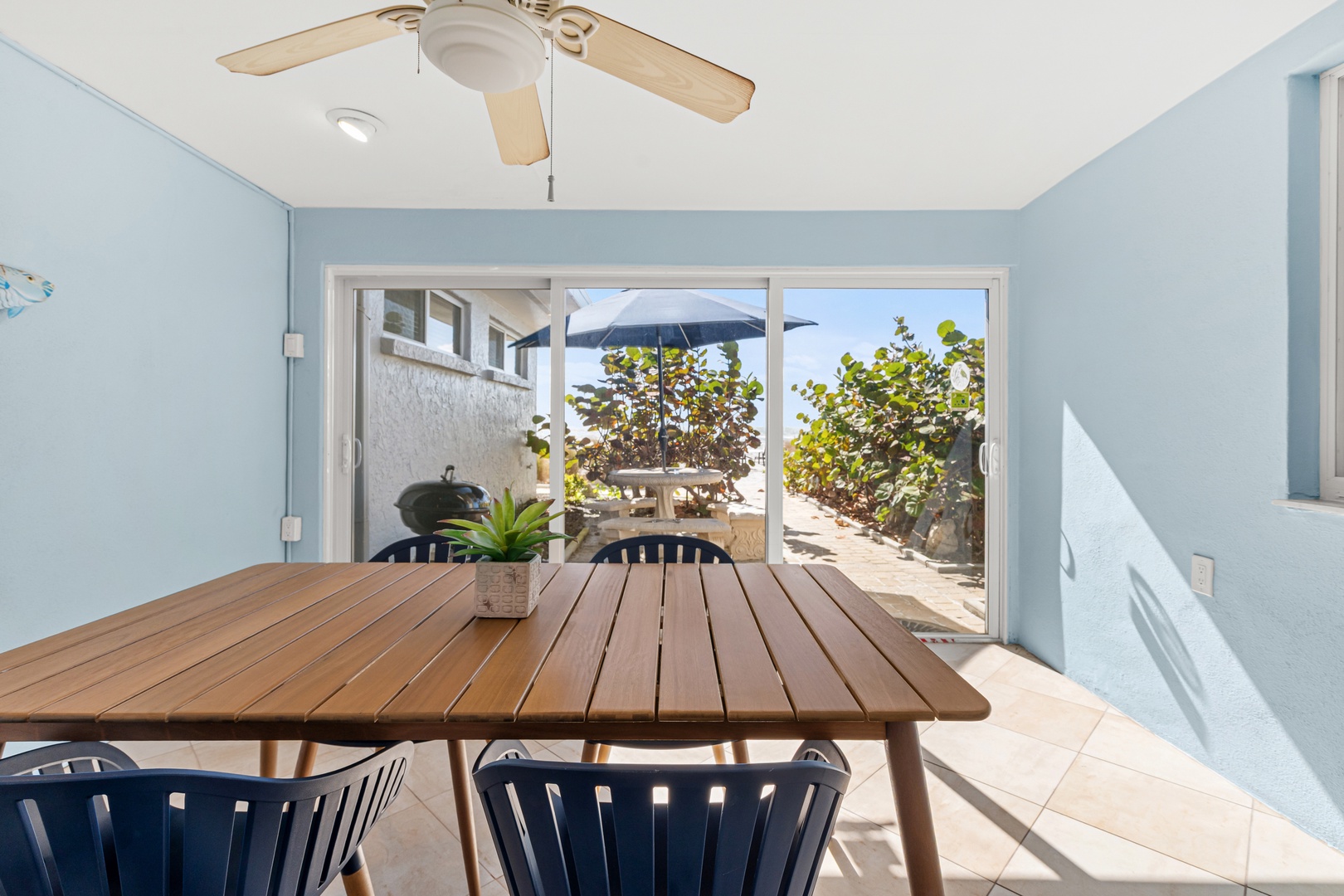 Gather around this inviting wooden dining table where ocean breezes flow through sliding doors to your private patio sanctuary.