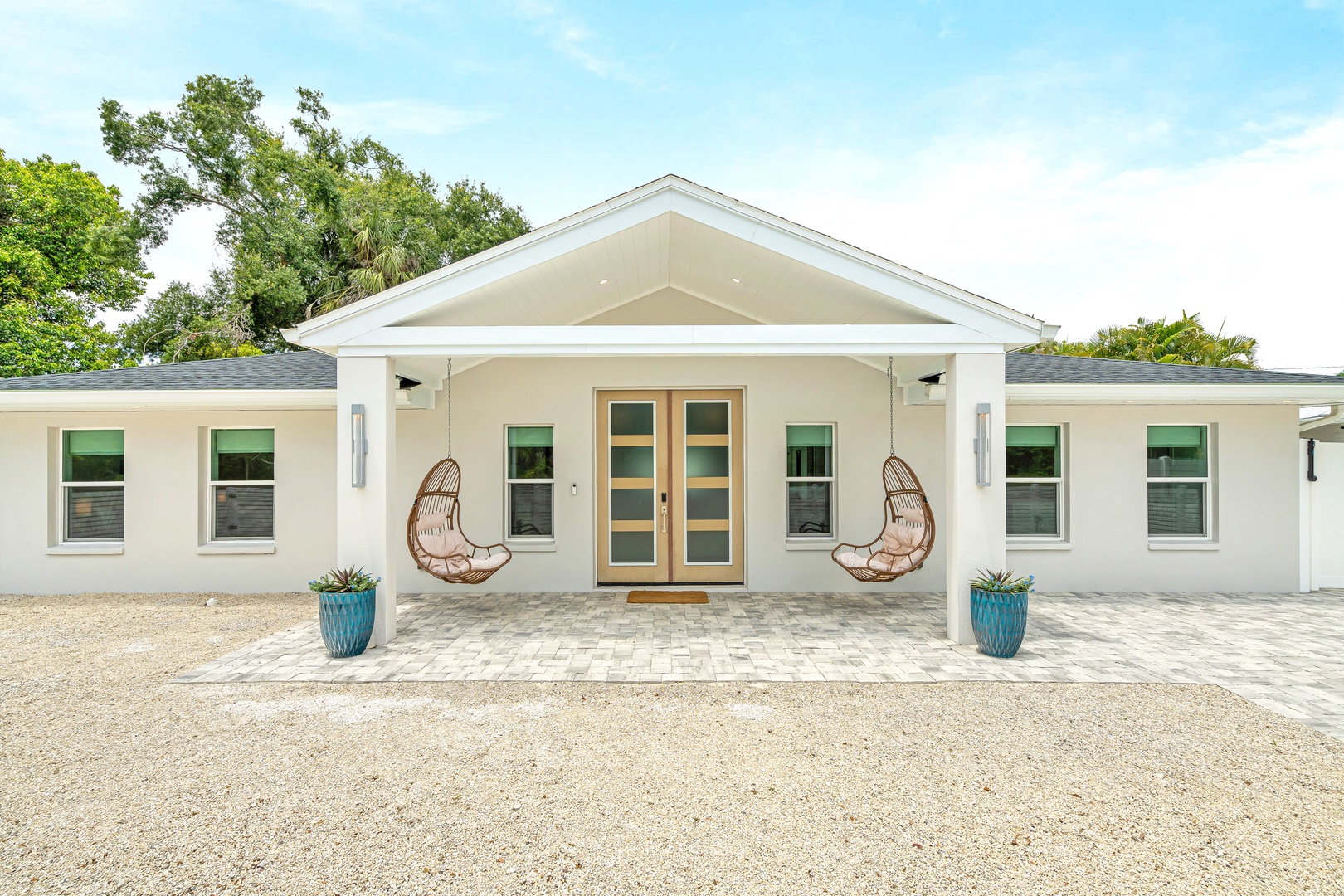 The charming façade welcomes you with its coastal-inspired architecture, featuring a covered entry with decorative hanging egg chairs.