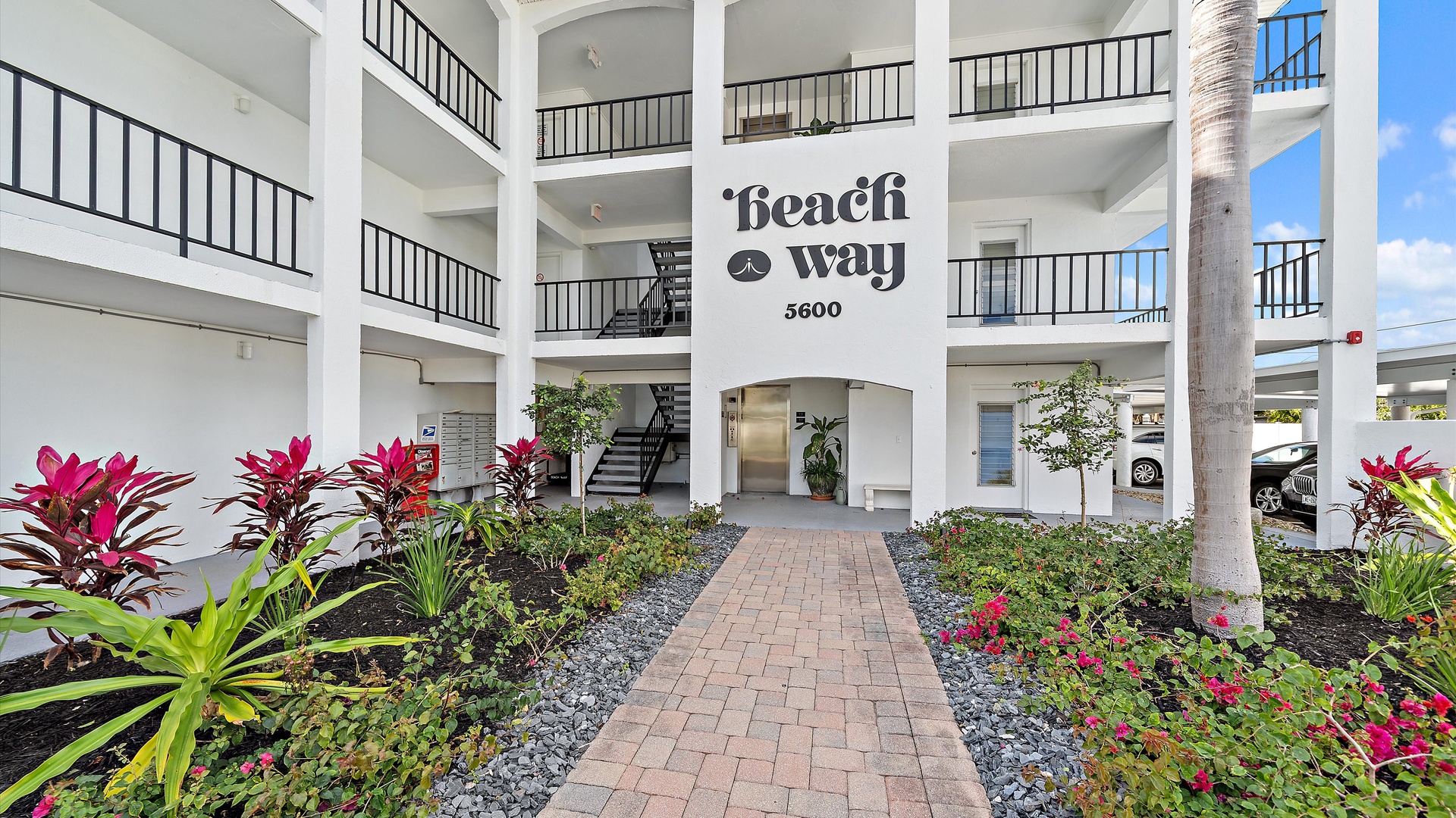 Welcoming entrance to Beach Way property featuring tropical landscaping and contemporary coastal architecture.