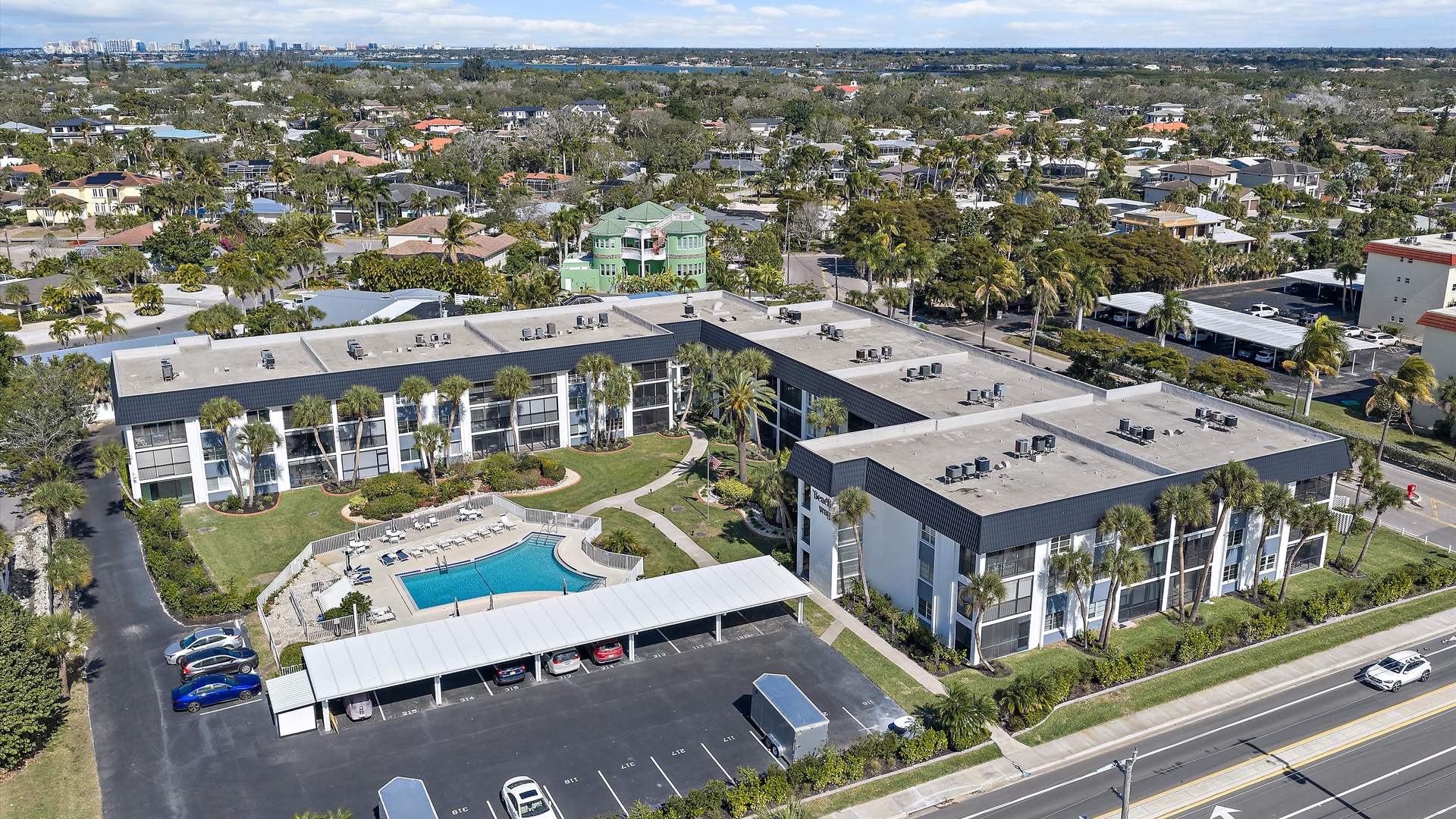 Aerial view of the property showcasing modern architecture nestled in a peaceful residential neighborhood with abundant parking and outdoor amenities.