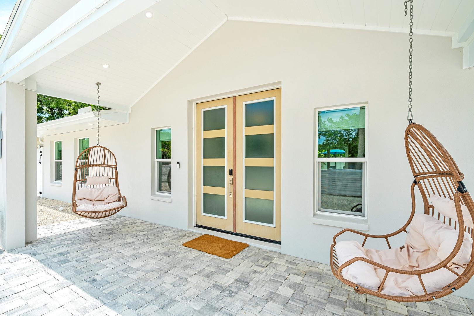 A covered and welcoming entry with two hanging egg chairs for relaxing or morning coffee.