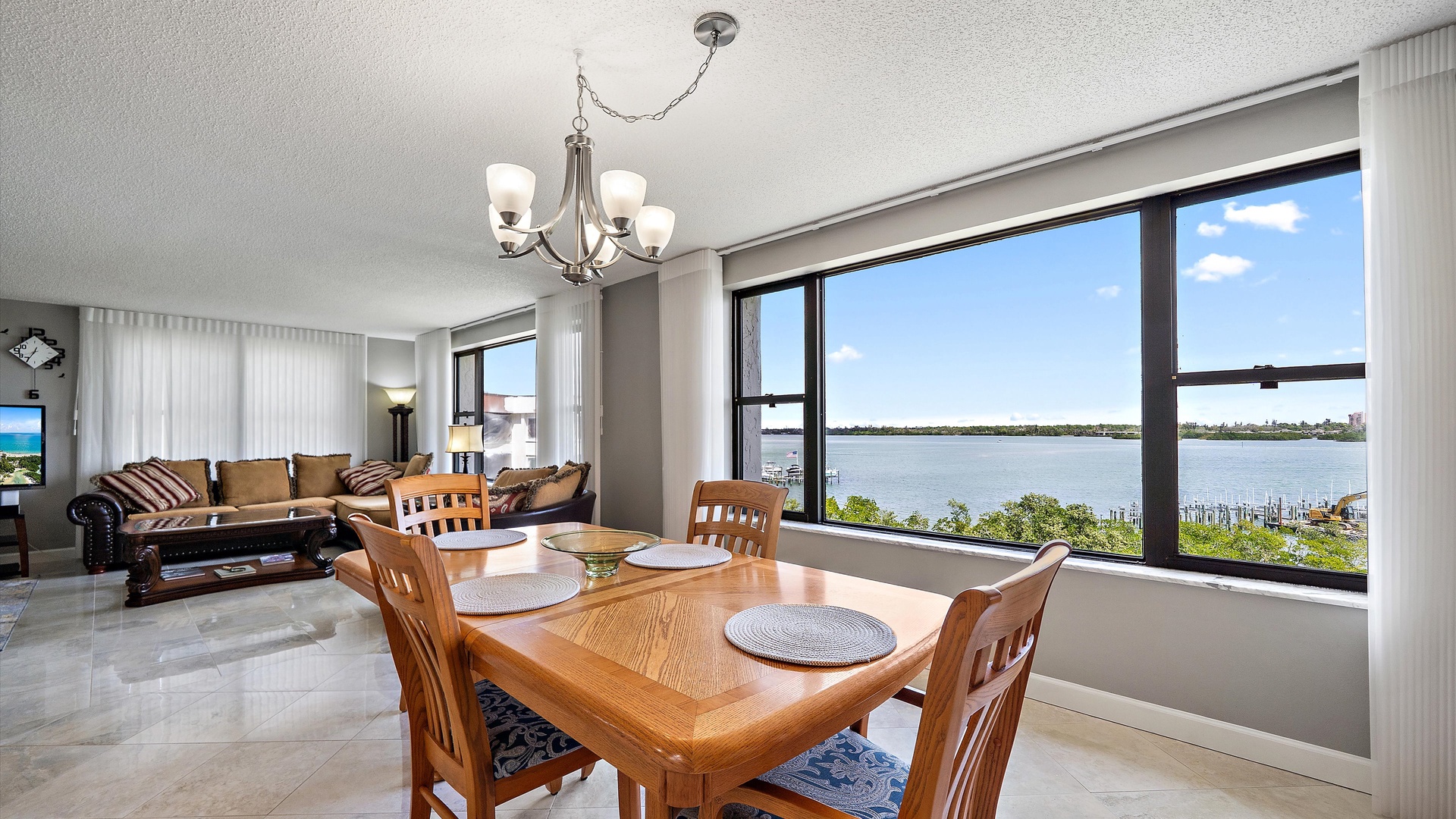Enjoy meals with stunning water views through floor-to-ceiling windows in your bright, open-concept living space with elegant furnishings.