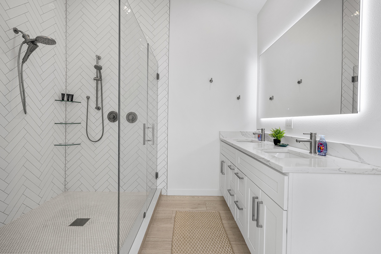 Step into your modern sanctuary with a bright, elegant bathroom featuring a spacious walk-in shower, dual vanities with LED-lit mirrors, and sophisticated herringbone tile that adds a touch of luxury.