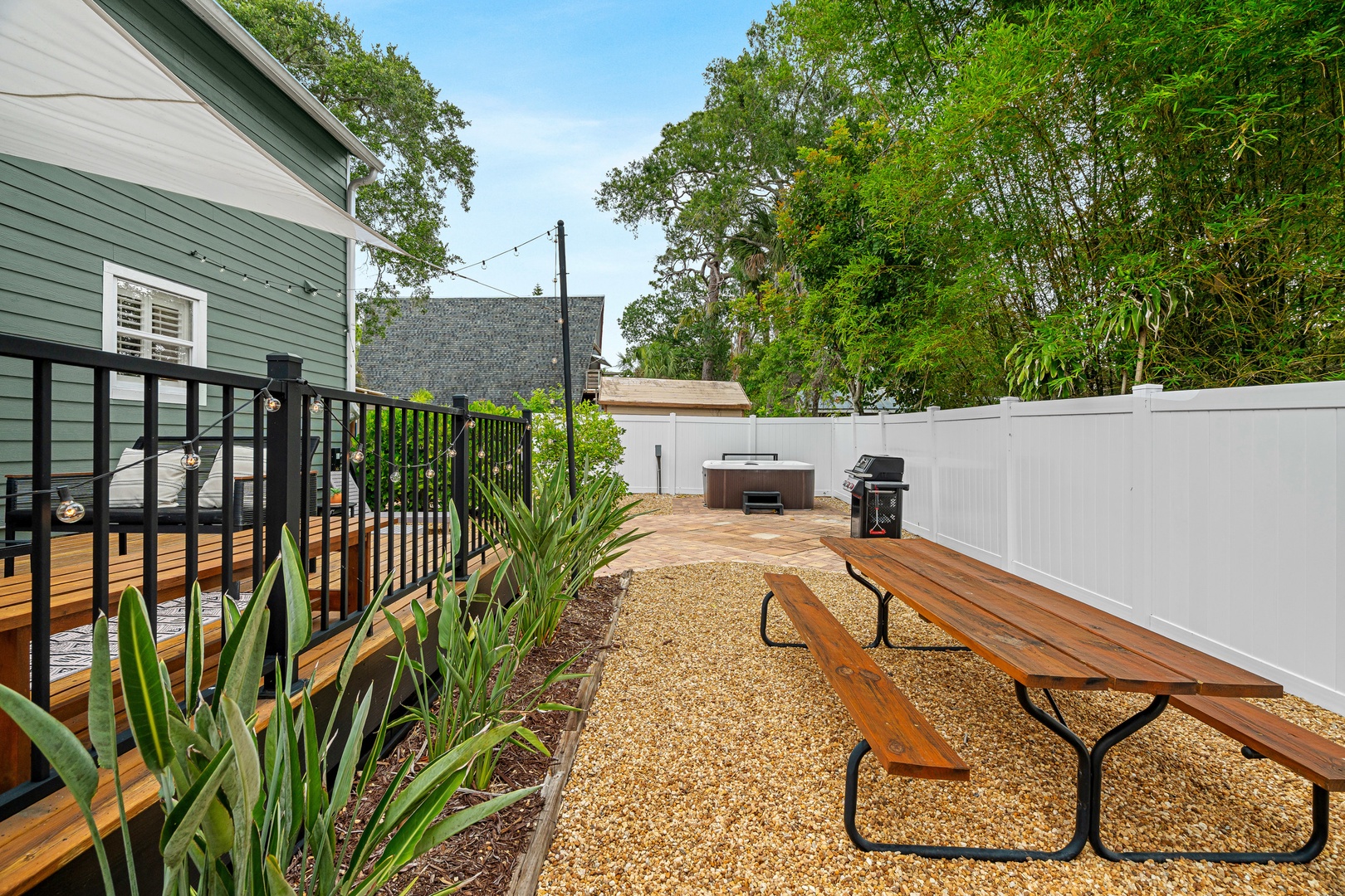 Your private backyard oasis features a spacious patio with picnic-style seating, a relaxing hot tub, and BBQ facilities—perfect for outdoor dining and unwinding under the trees.