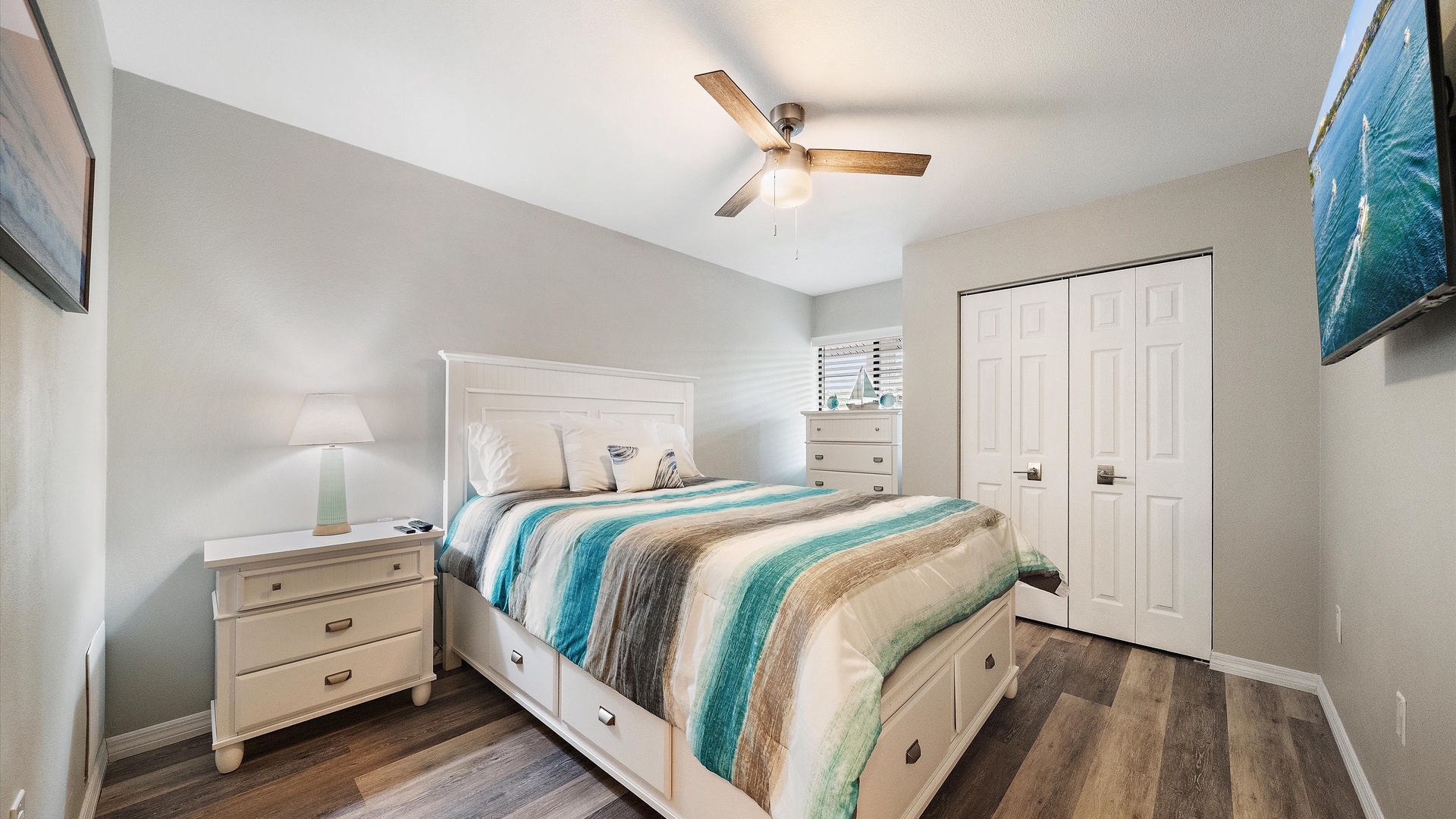 Drift off in this calming coastal guest bedroom, where soft hues and gentle breezes from the ceiling fan create your perfect retreat. The coastal-themed decor and plush bedding invite you to unwind.