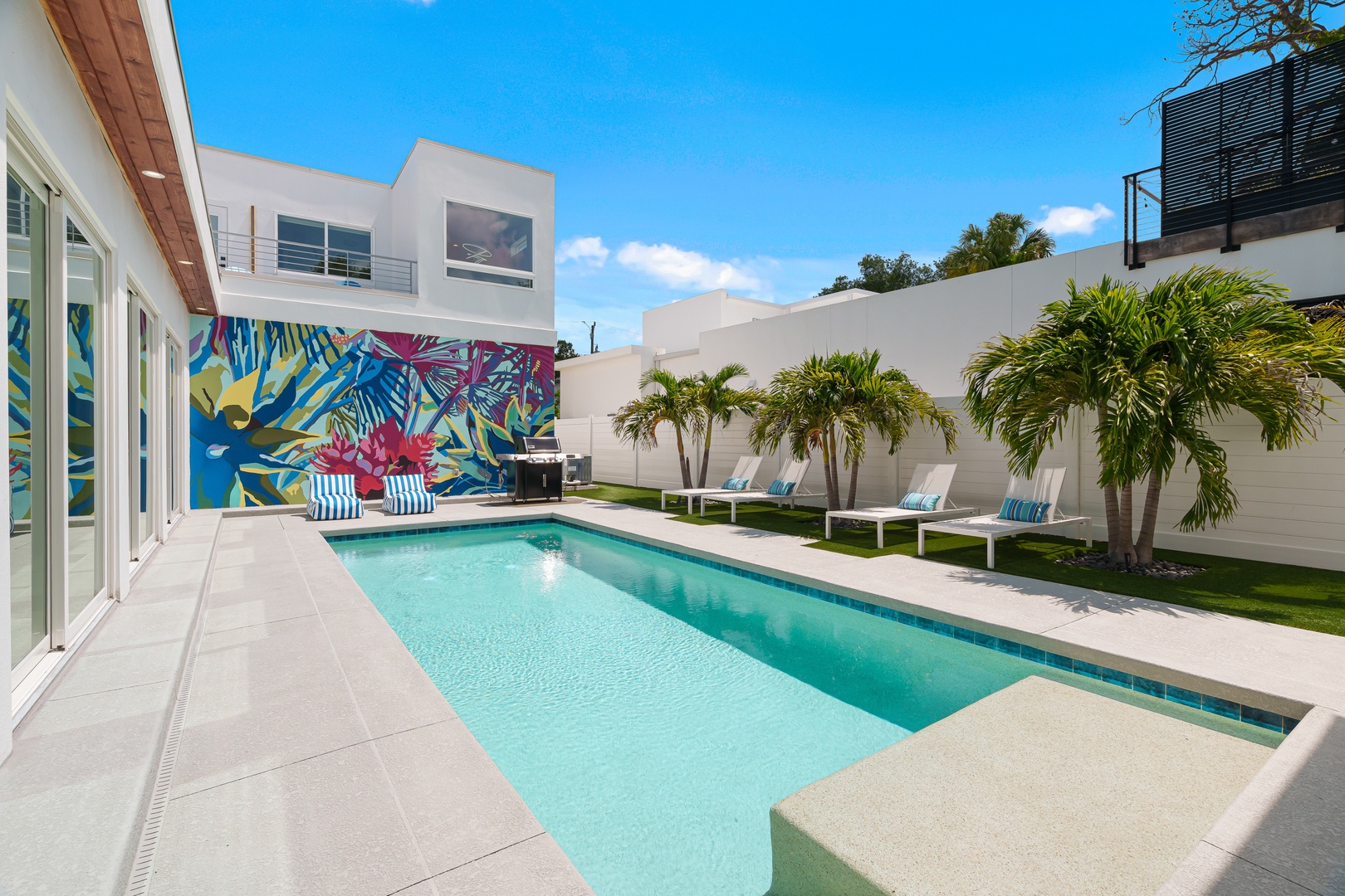 Your private oasis awaits: soak up the sun by your sparkling pool, lounge on crisp white chairs beneath swaying palms, and enjoy vibrant tropical art that makes every moment feel like a vacation.