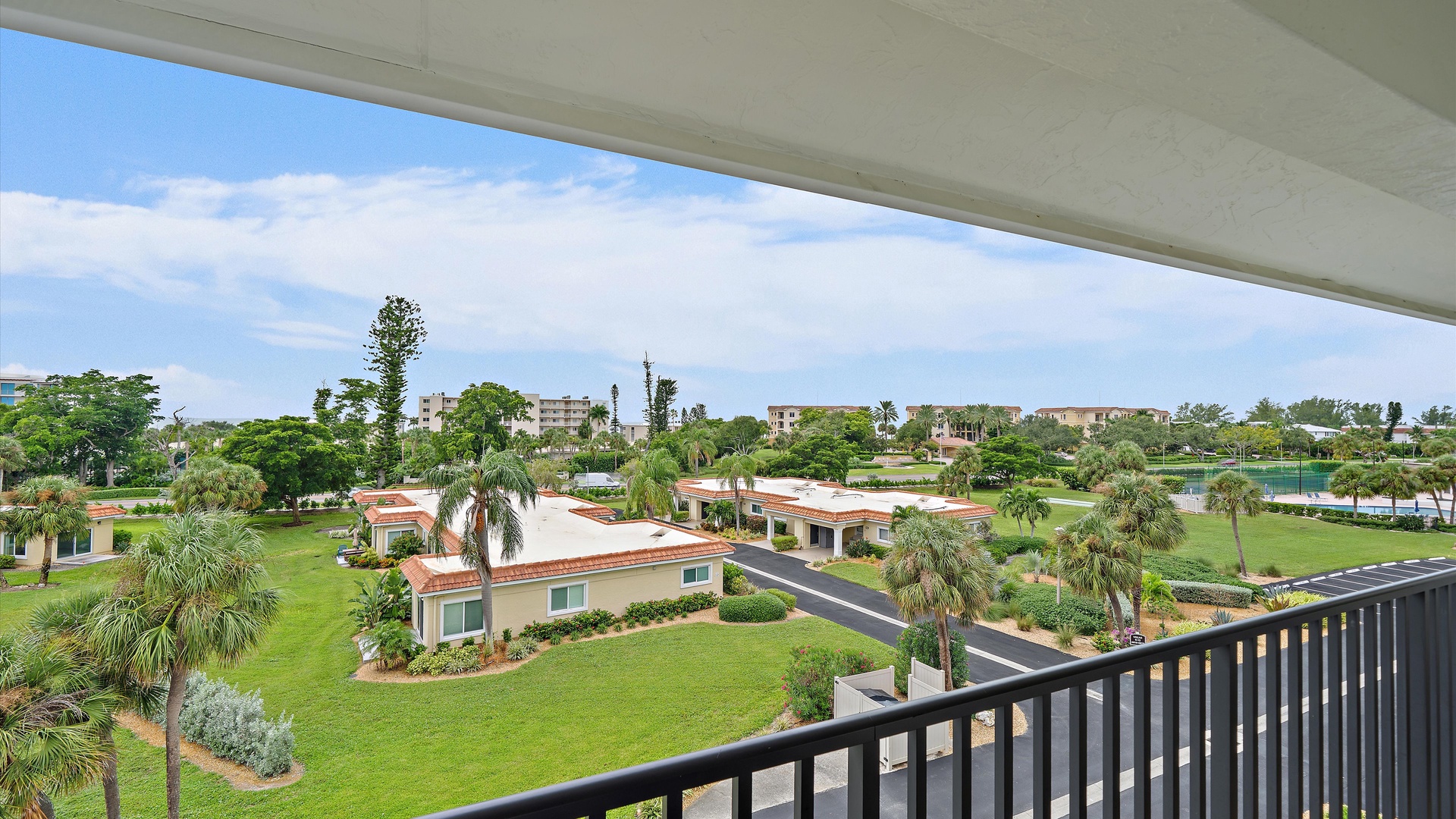 A different perspective on Longboat Key, with palms, green lawns, and neighboring homes beyond the building. The surrounding island neighborhood adds to Windward Bay’s residential feel.