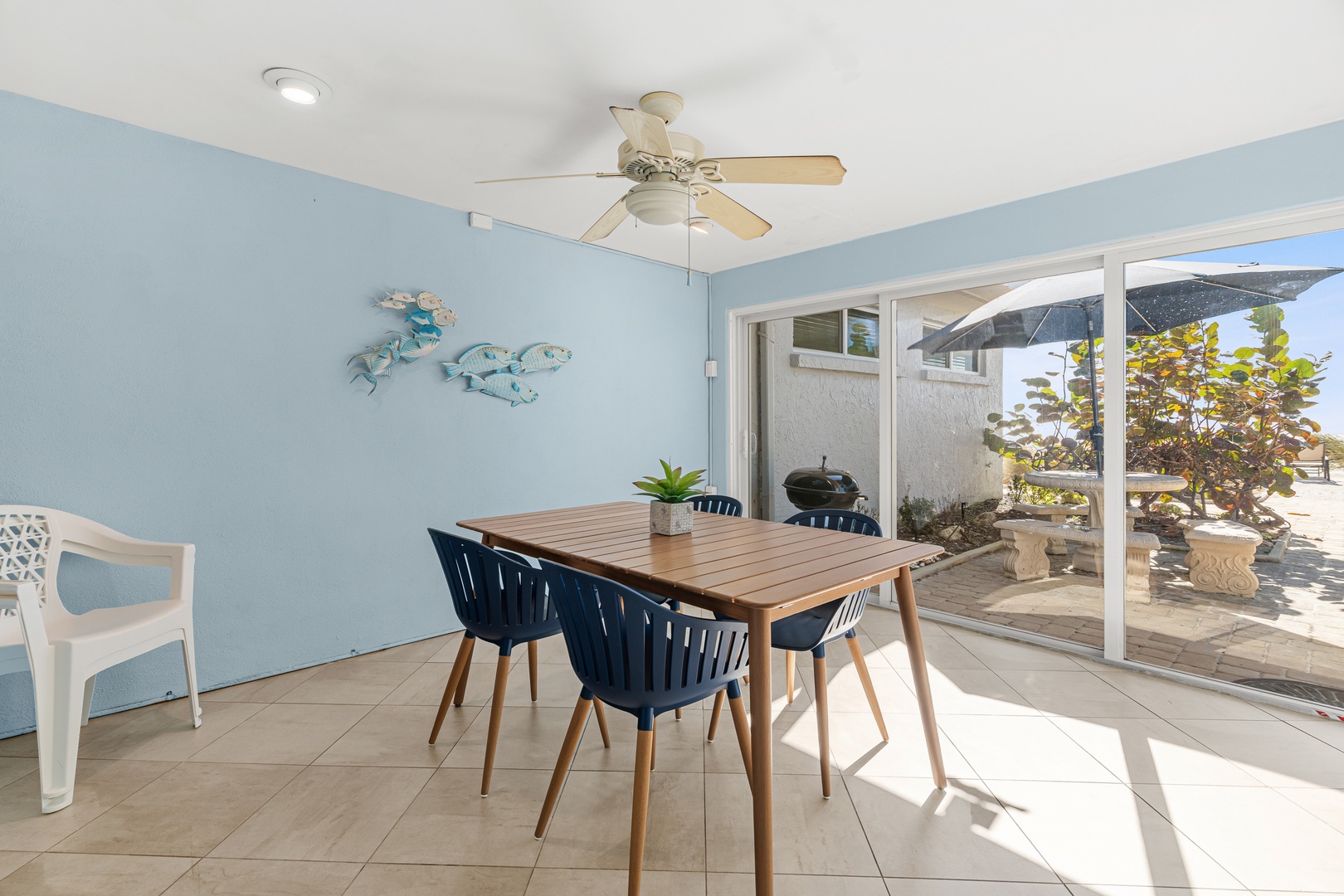 Your bright dining space features coastal charm with ocean-themed wall art and opens to a private patio perfect for outdoor grilling.