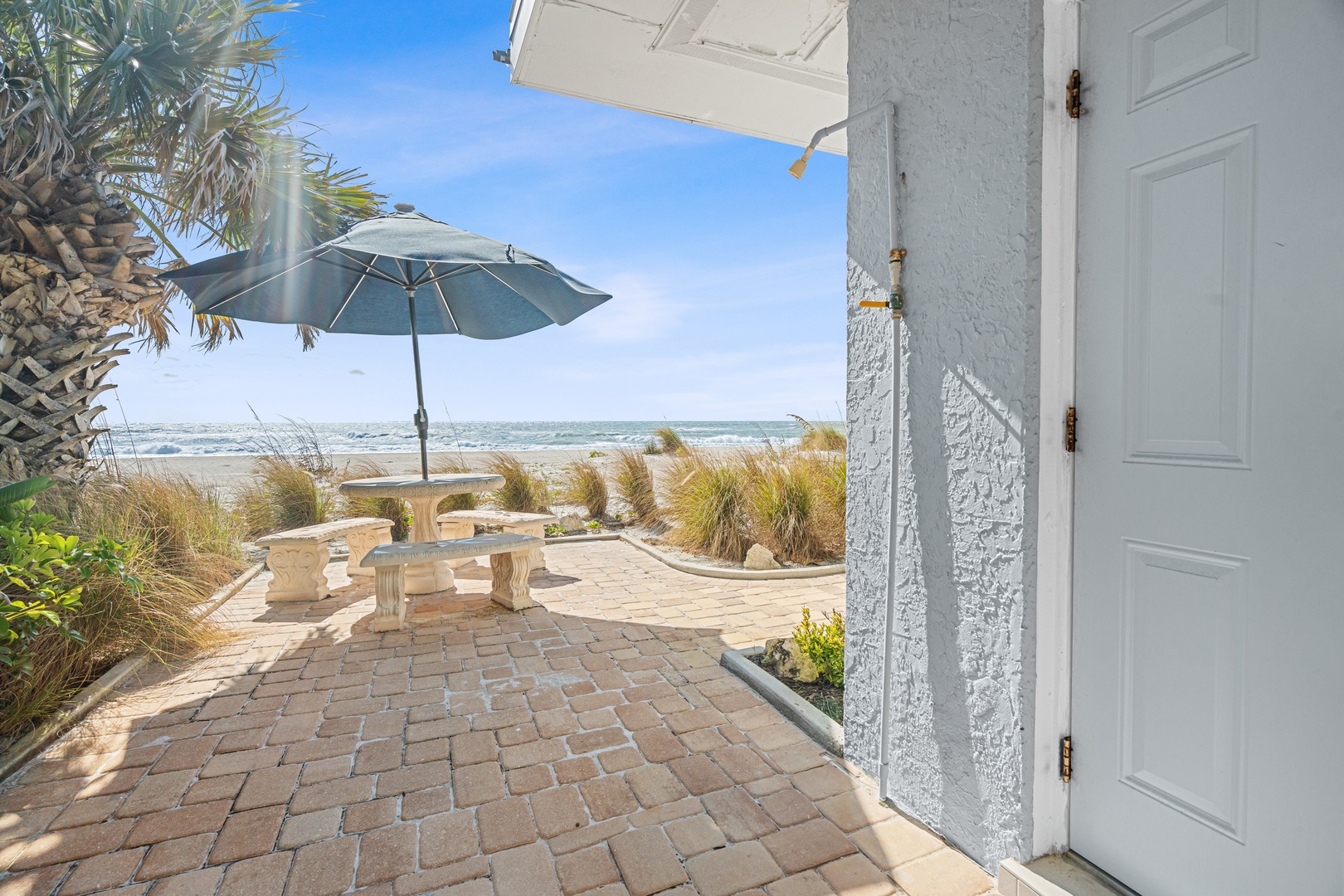 Step onto your private beachfront patio where ocean breezes meet comfortable seating under swaying palms.