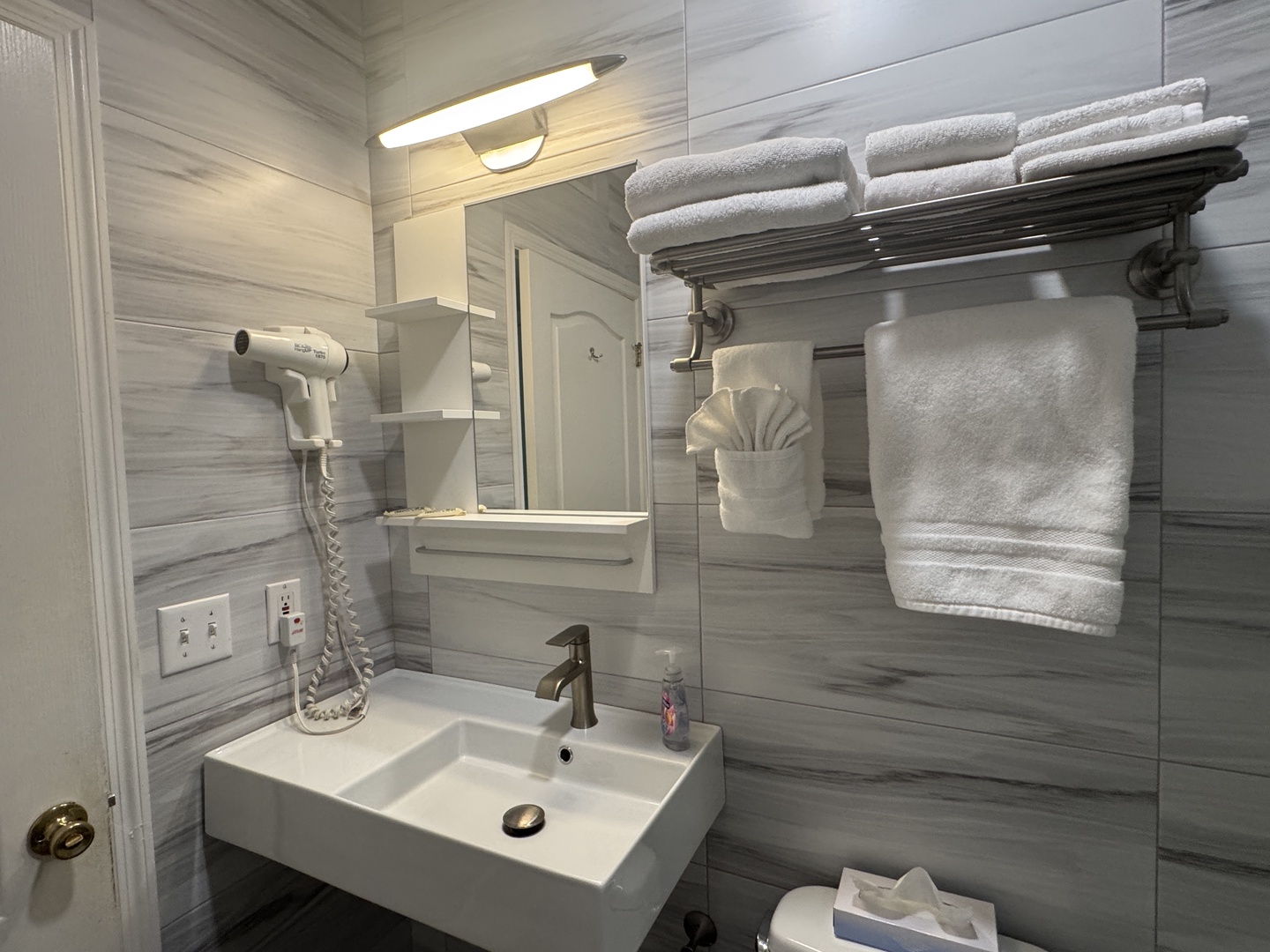 Your private bathroom features modern fixtures, crisp linens, and thoughtful amenities like a hair dryer—designed to help you feel refreshed and at home.