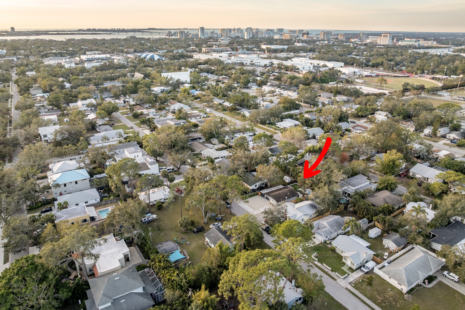 Aerial view of the peaceful residential neighborhood with tree-lined streets and the downtown skyline visible in the distance.