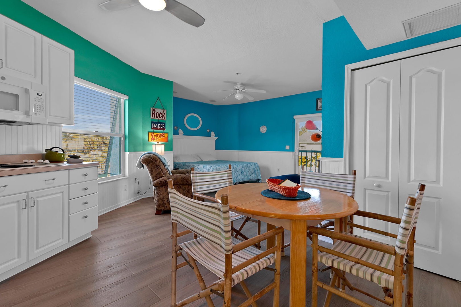 Bright turquoise and blue walls surround your dining space where you can gather for meals around a warm wooden table, then relax on the cozy daybed by the window or unwind in the armchair with a good book.