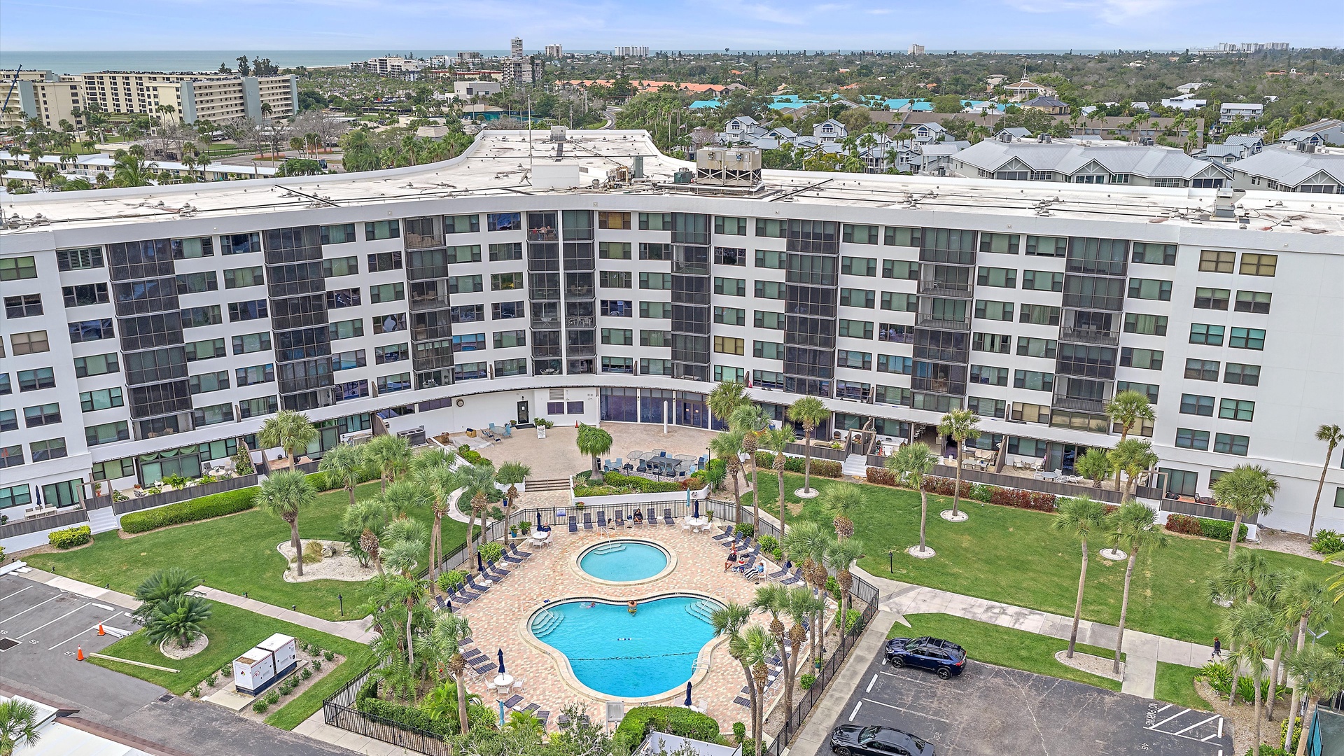 Aerial view of the large curved resort building and surrounding residential area with lush tropical landscaping throughout the neighborhood.