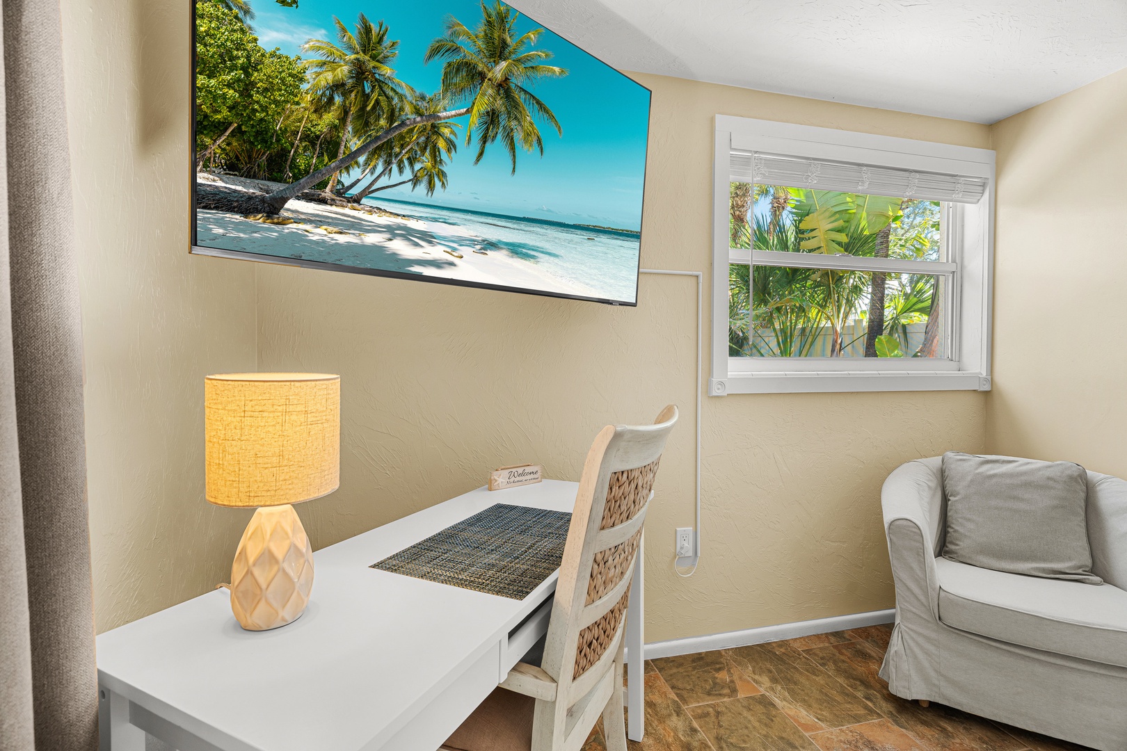Step into your peaceful workspace, where tropical greenery frames the window and natural light fills the room, creating the perfect spot to unwind or catch up on plans.