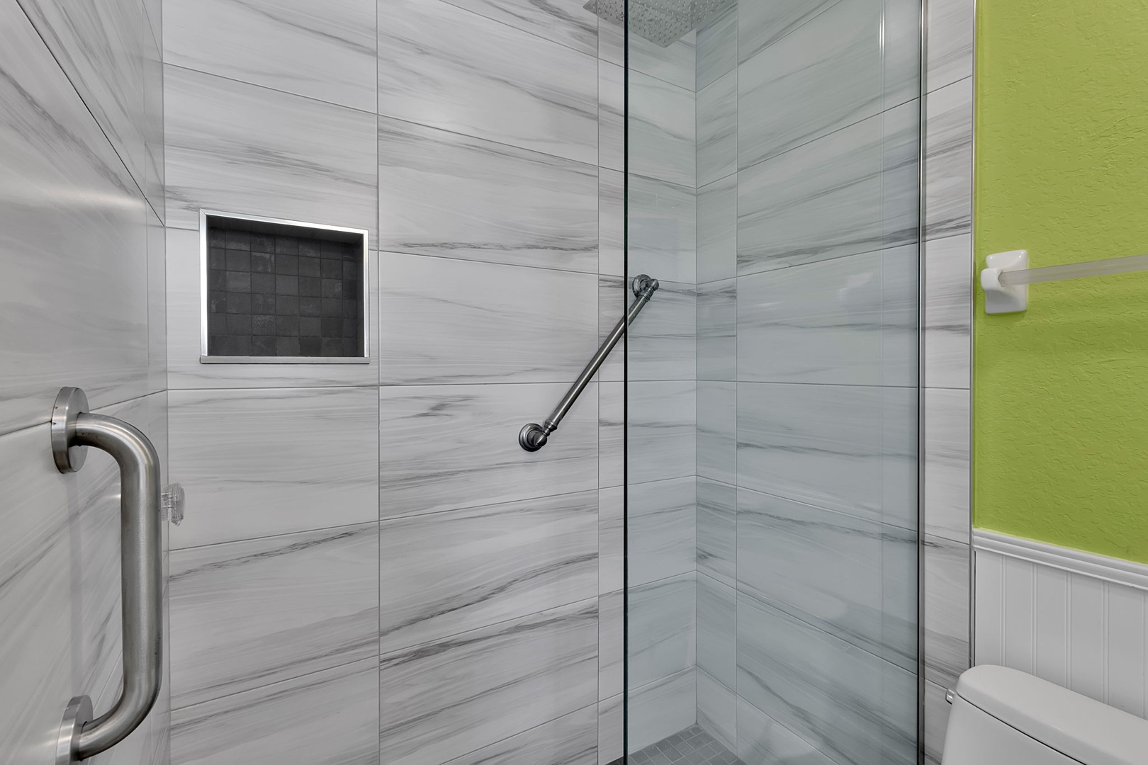A spacious walk-in shower features elegant stone-look tile and a thoughtfully designed handheld showerhead for your comfort.