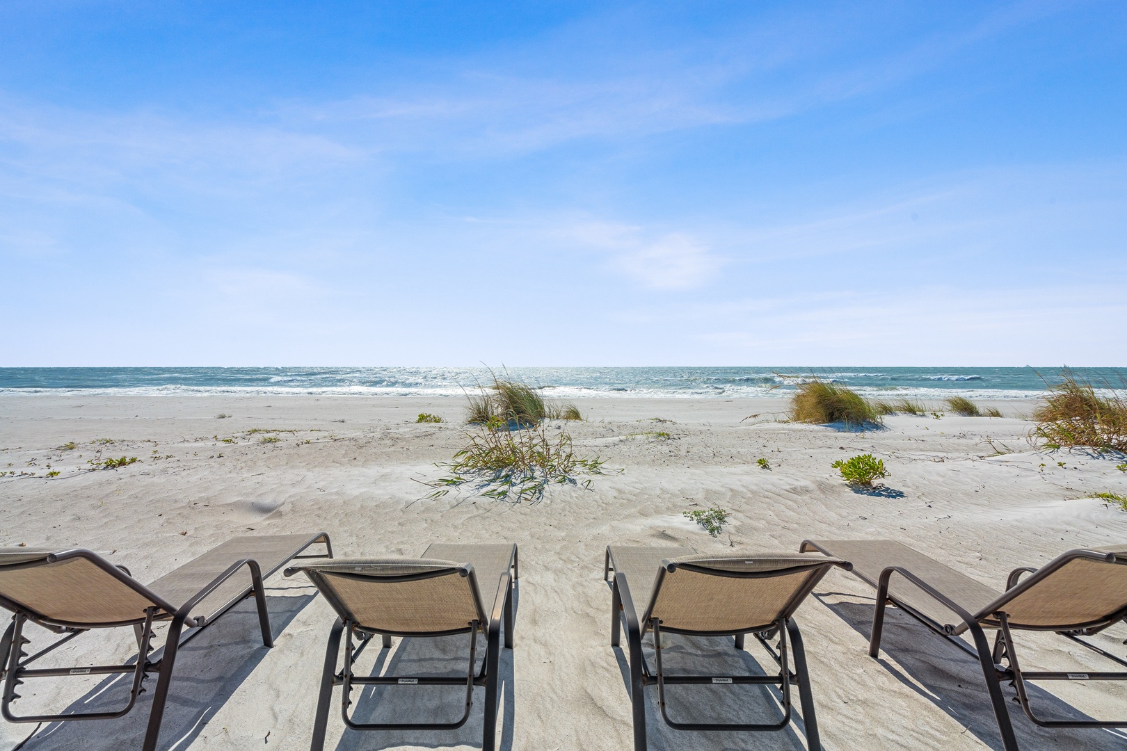 Pristine beachfront with beach chairs positioned for direct ocean access and endless coastal views.