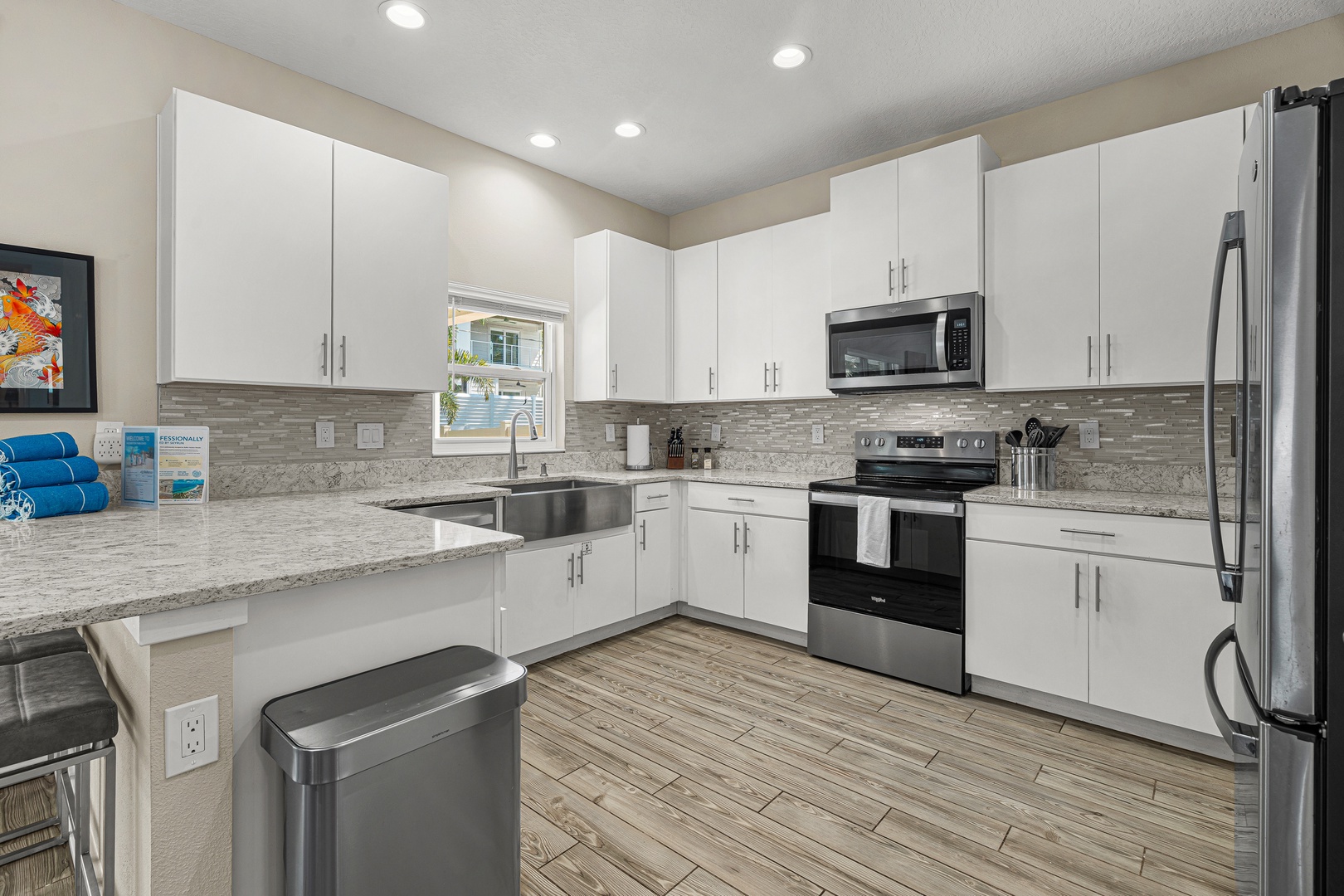 Step into your fully equipped modern kitchen with sleek white cabinetry, granite countertops, and stainless steel appliances—perfect for preparing your favorite meals or morning coffee during your stay.