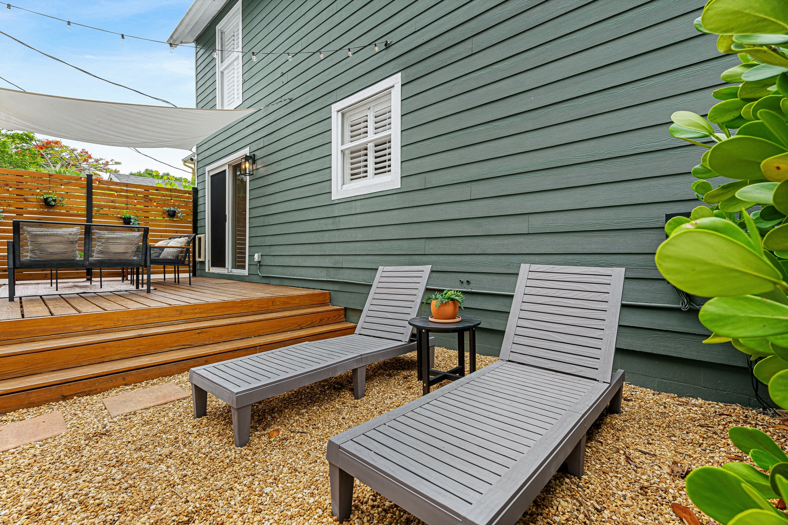 A private outdoor retreat where you can soak up sunshine on comfortable loungers, steps from your deck with dining space shaded by fabric sails and tropical greenery.