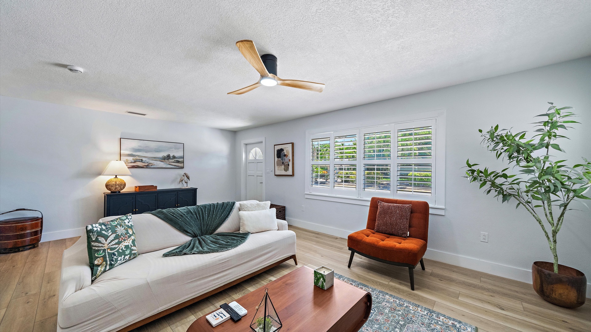 Settle in and unwind in your bright living space with natural light streaming through plantation shutters, a cooling ceiling fan overhead, and thoughtfully curated décor that blends coastal calm with modern comfort.