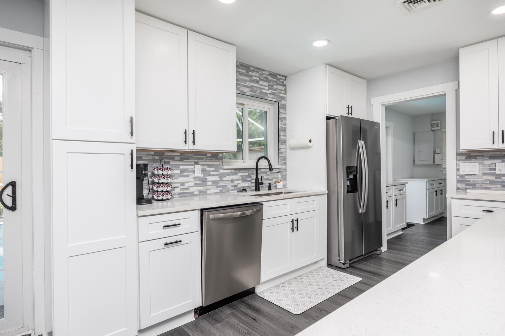 You'll love preparing meals in this bright, modern kitchen featuring sleek white cabinets, granite countertops, and stainless steel appliances.