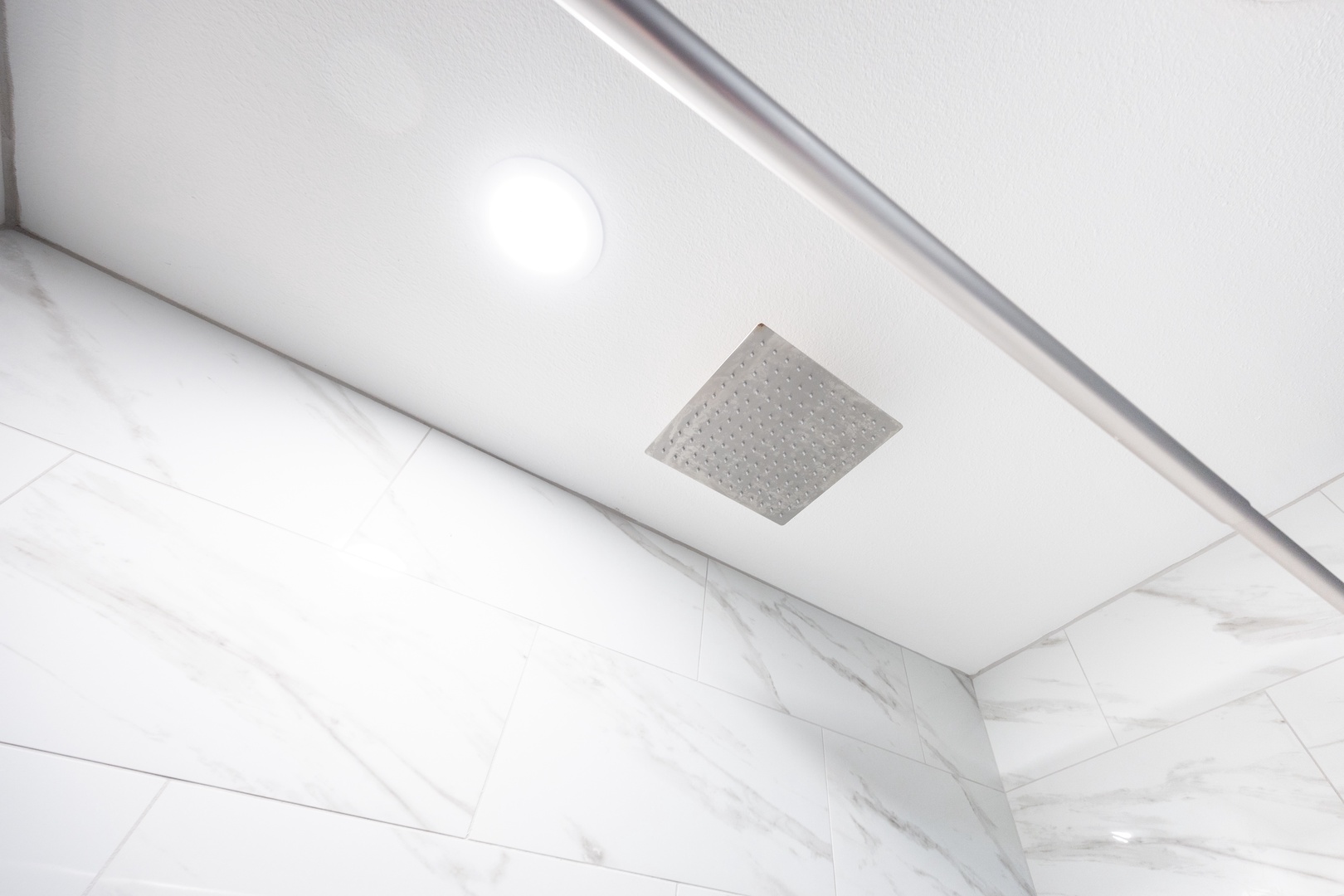 Step into your luxurious marble-clad shower with rainfall showerhead for pure relaxation.
