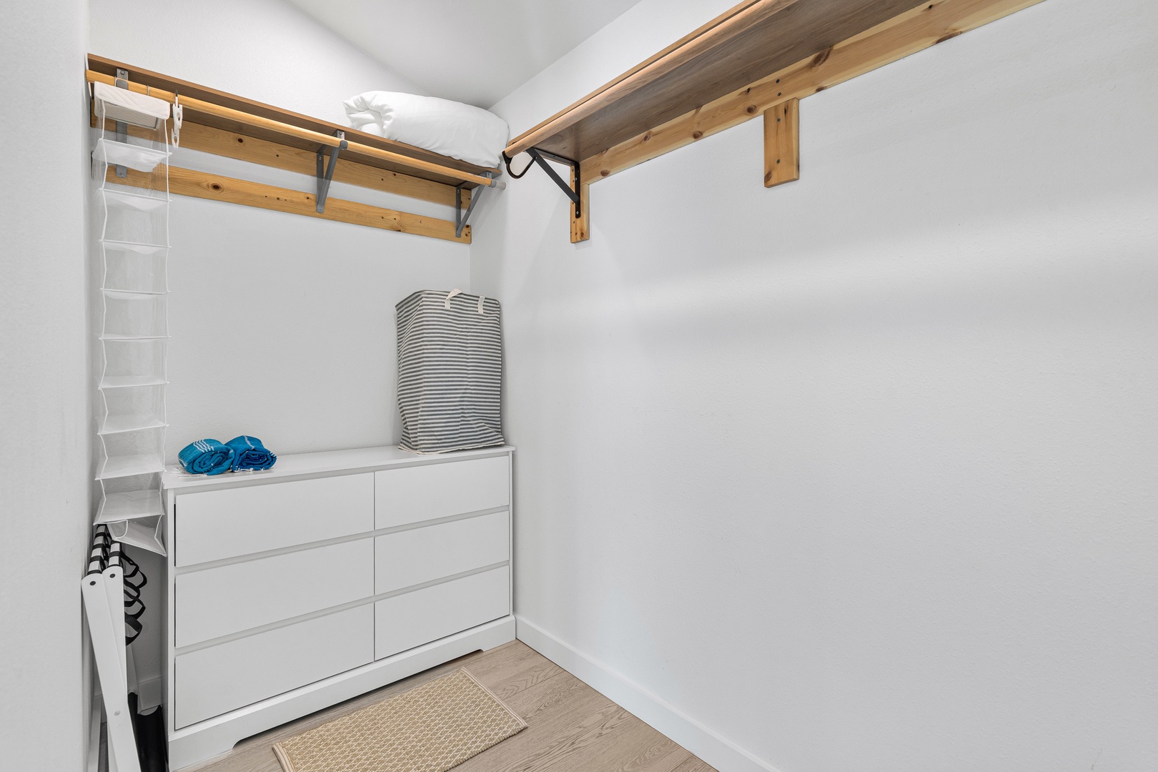 Store your belongings in this organized walk-in closet with custom wood shelving, a spacious dresser, and hanging storage to keep everything tidy during your stay.