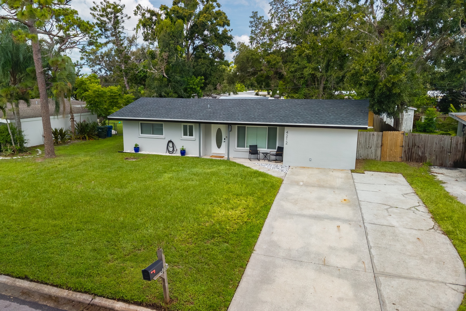 A charming single-story home with spacious lawn and convenient driveway parking, nestled in a peaceful tree-lined neighborhood.