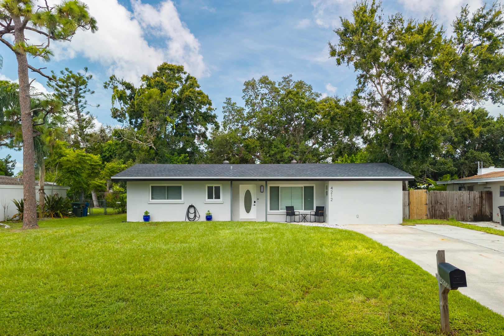 Charming single-story home nestled among mature trees with spacious front yard and covered entrance porch.
