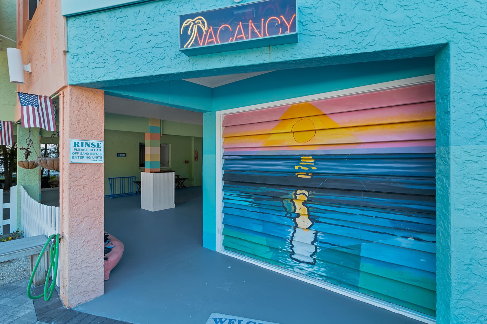The vibrant turquoise exterior and cheerful painted sunset mural greet you at the property's welcoming entrance, setting a relaxed, beachside tone from the moment you arrive.