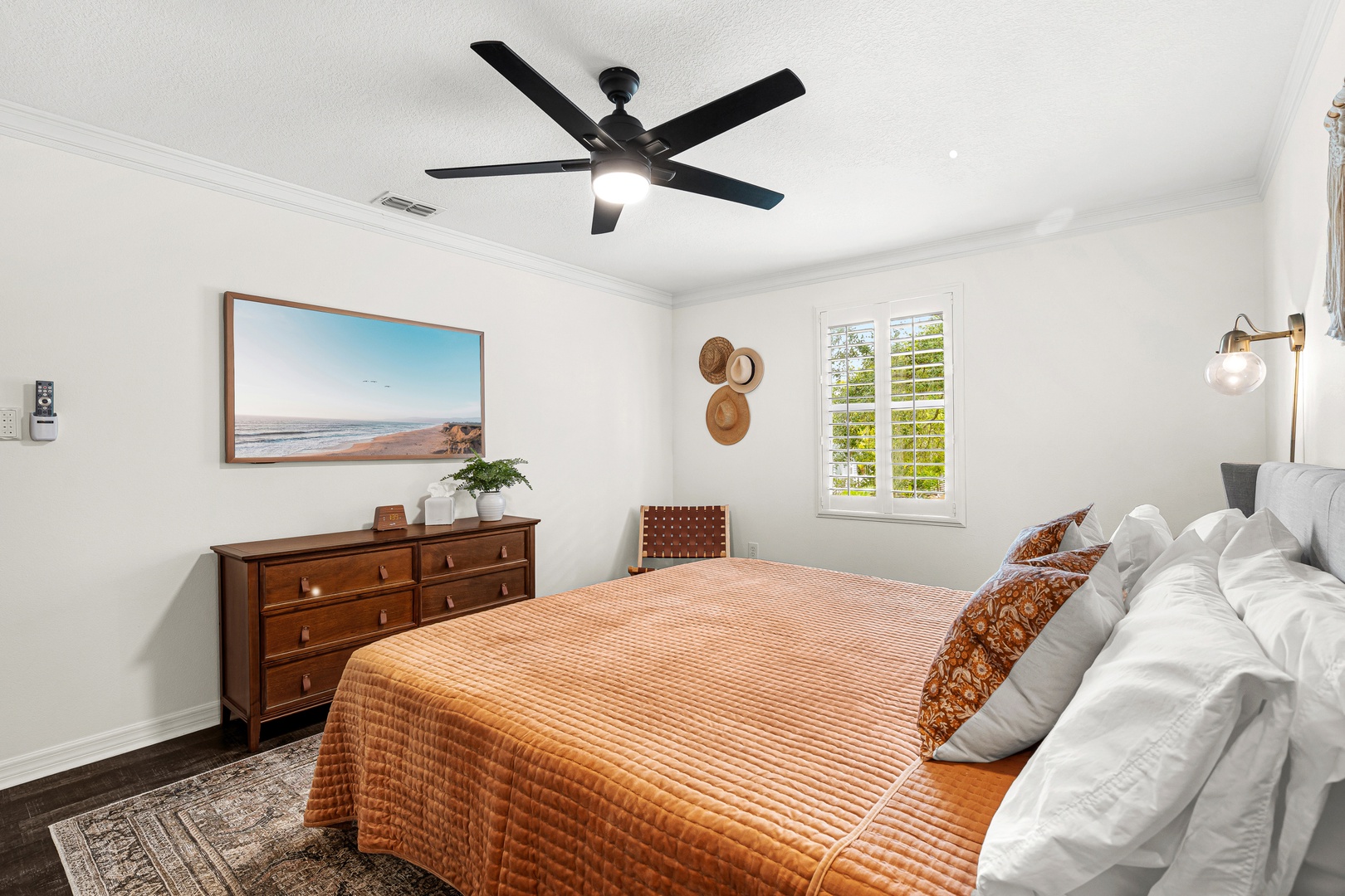 Drift off in this bright, coastal-inspired bedroom with plush bedding, soothing artwork, and a ceiling fan to keep you comfortable year-round.