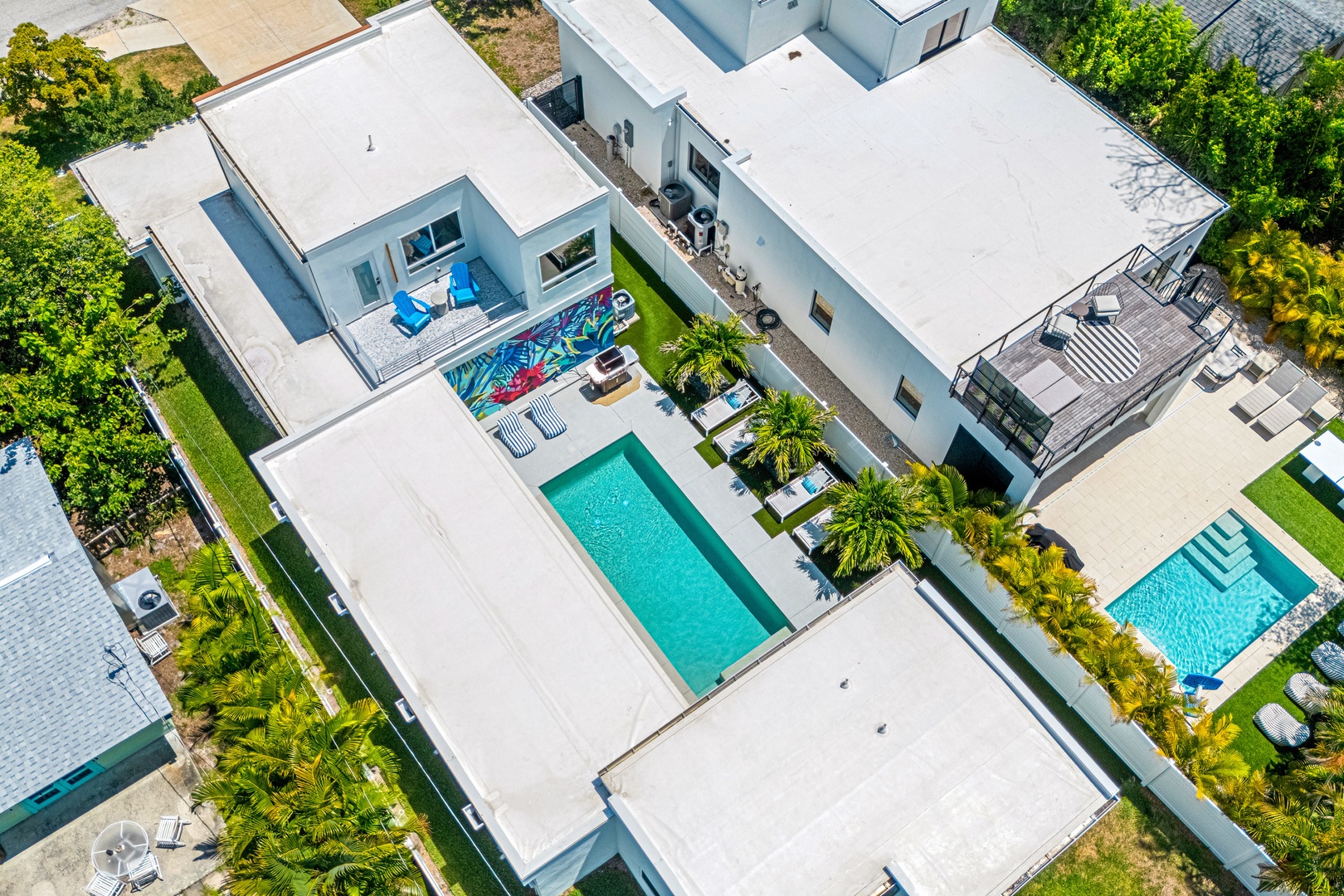 Modern vacation retreat featuring sparkling pool, lush tropical landscaping, and spacious outdoor living areas nestled in a peaceful residential neighborhood.