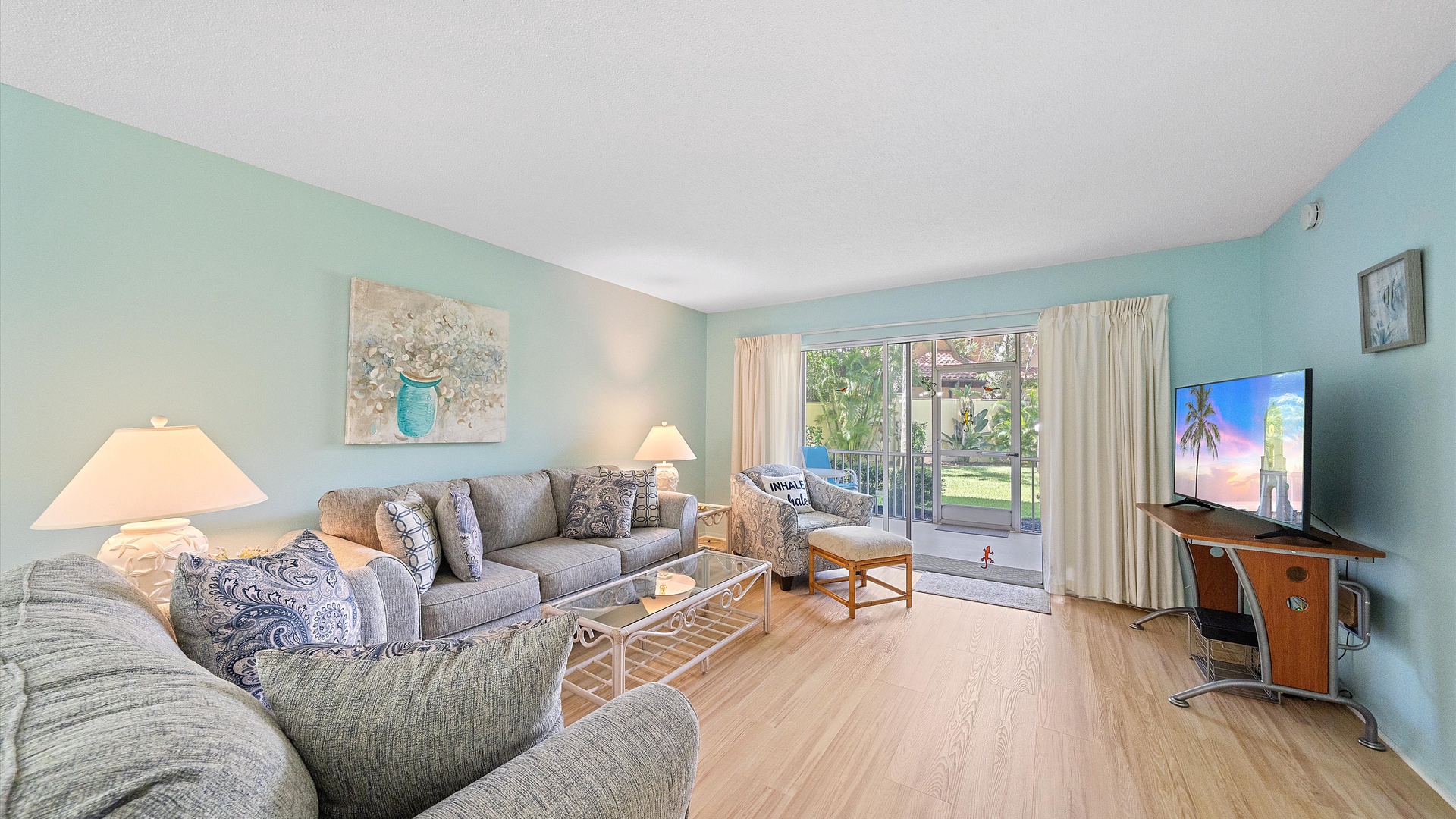 Unwind in your serene living space with soothing coastal hues, comfortable seating for the whole group, and sliding doors opening to your private balcony overlooking lush greenery and sunshine.