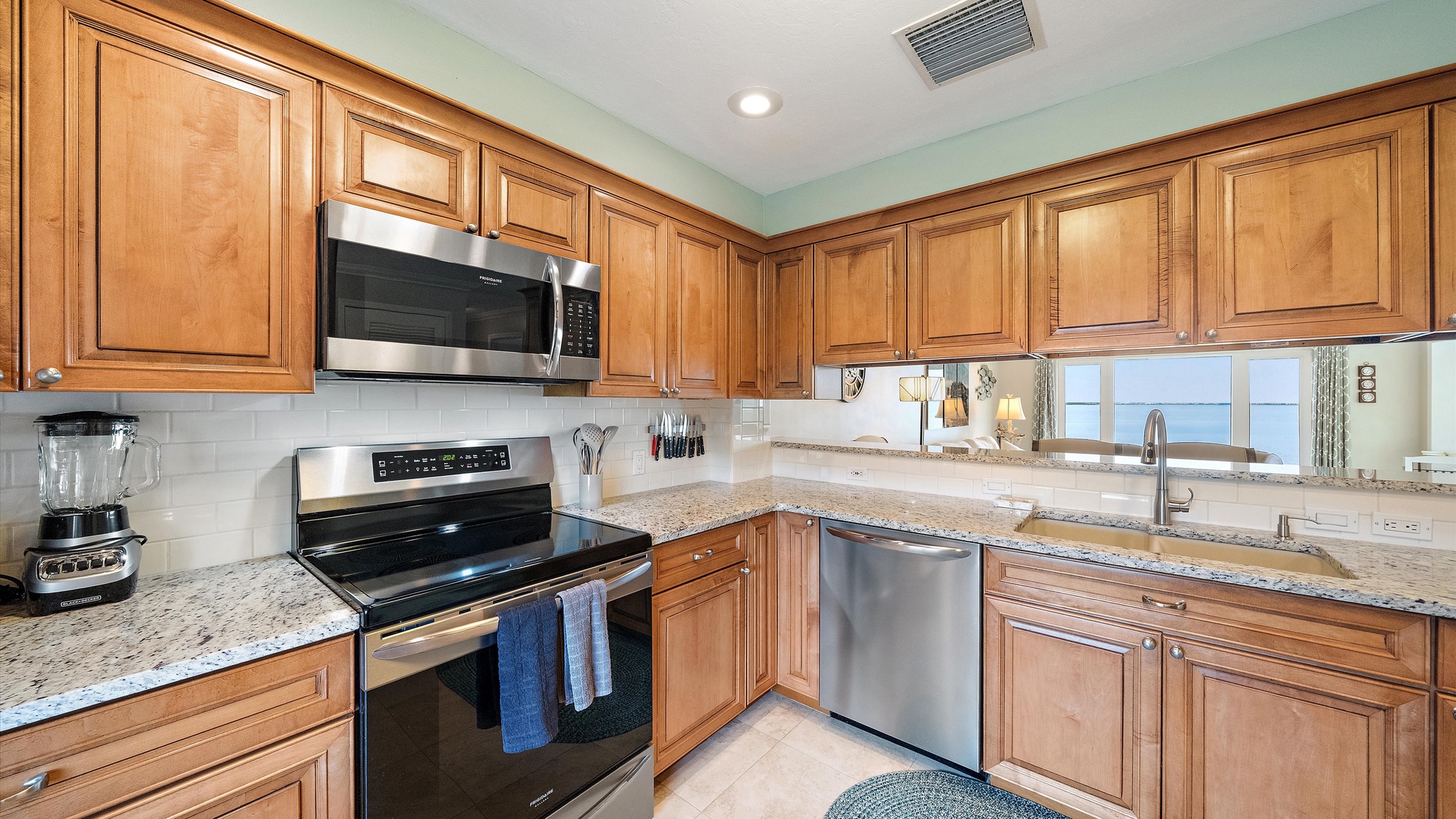 A well-equipped kitchen with a full-size range, microwave, and plenty of counter space. Warm cabinetry and granite finishes bring the same comfortable style found throughout the penthouse.