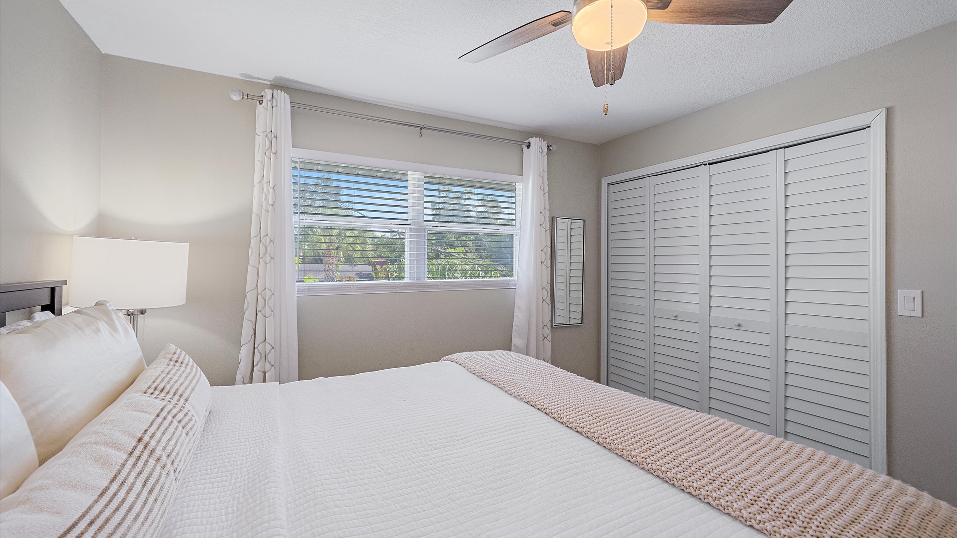 Wake up refreshed in this serene bedroom, where soft natural light and coastal breezes filter through your window, and a ceiling fan keeps you comfortable year-round.