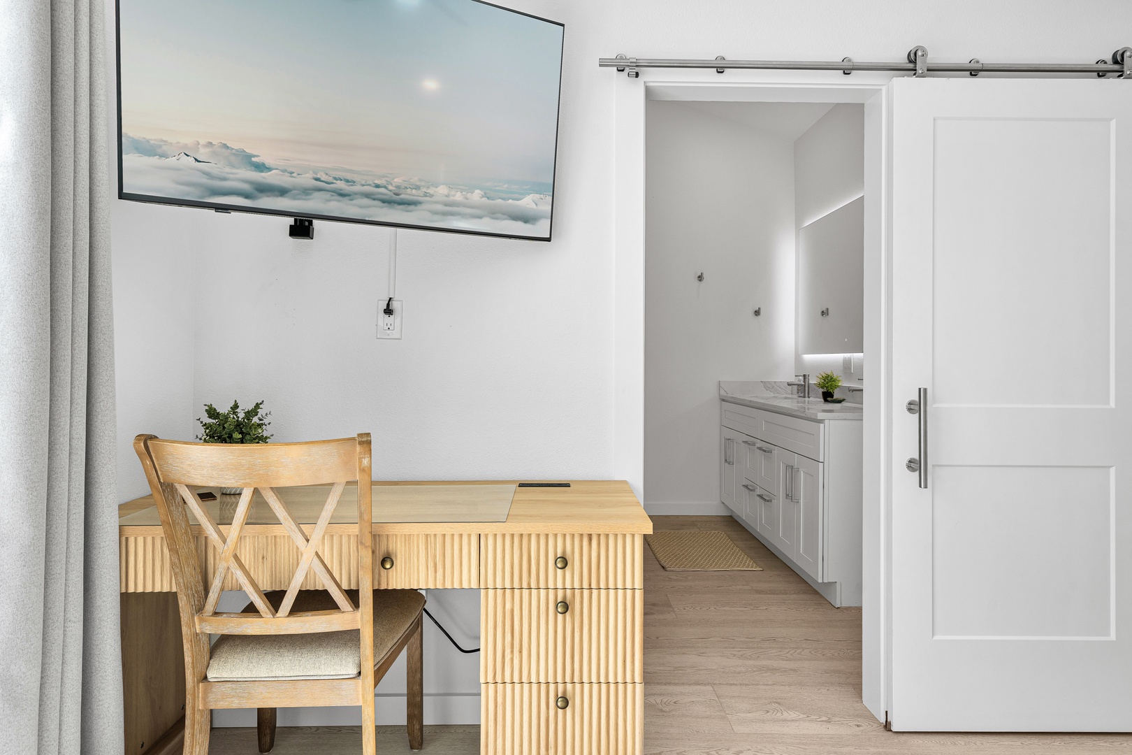 Settle into your personal workspace with serene coastal artwork and light-filled views. Your en-suite bathroom waits just beyond the stylish barn door, blending convenience with modern design.