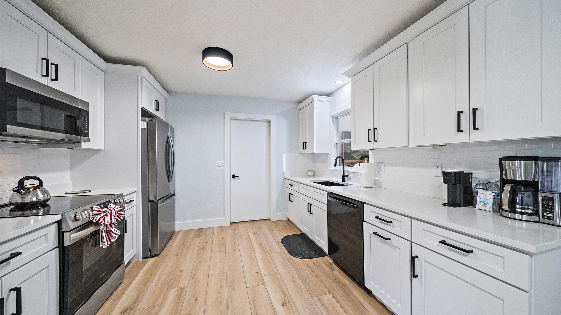 Your fully-equipped kitchen features modern stainless steel appliances and crisp white cabinetry, inviting you to prepare meals or brew morning coffee in a bright, welcoming space.