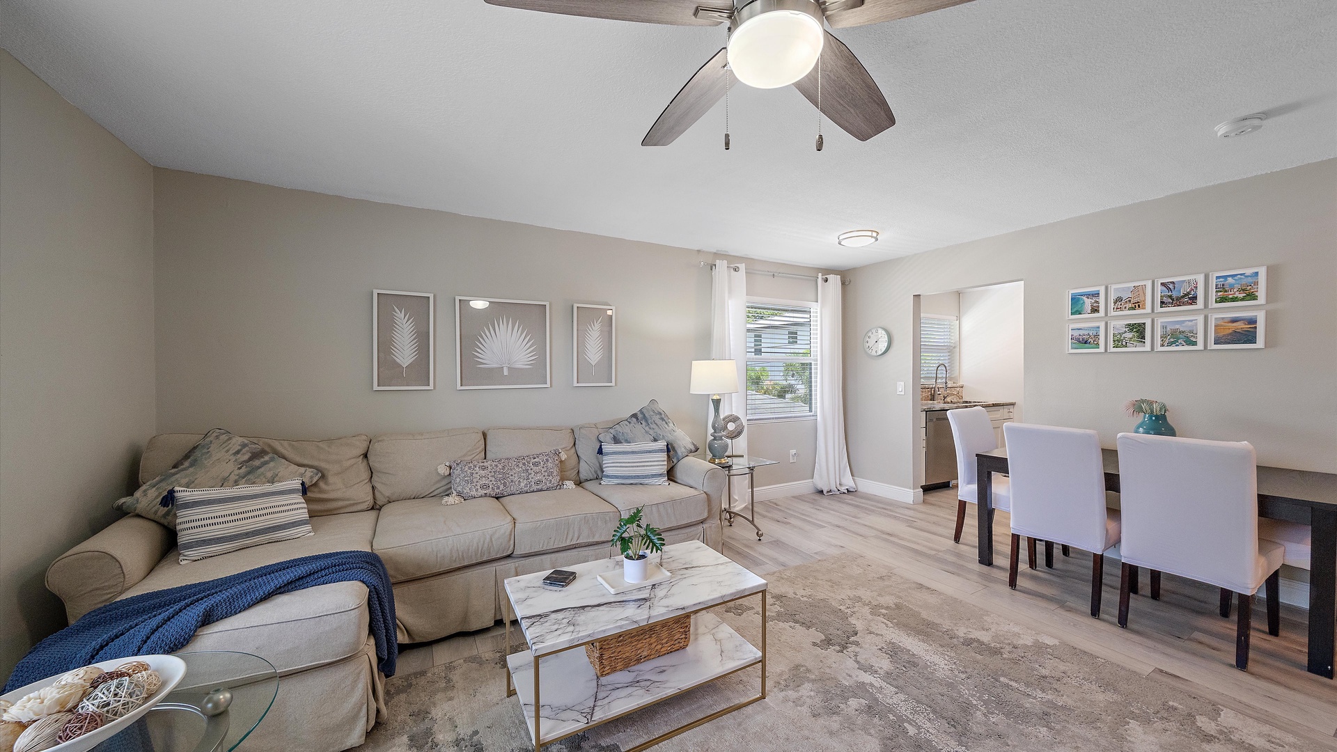 Settle into your spacious, sunlit living area where a plush sectional and dining table invite relaxed evenings and shared meals in coastal-inspired comfort.