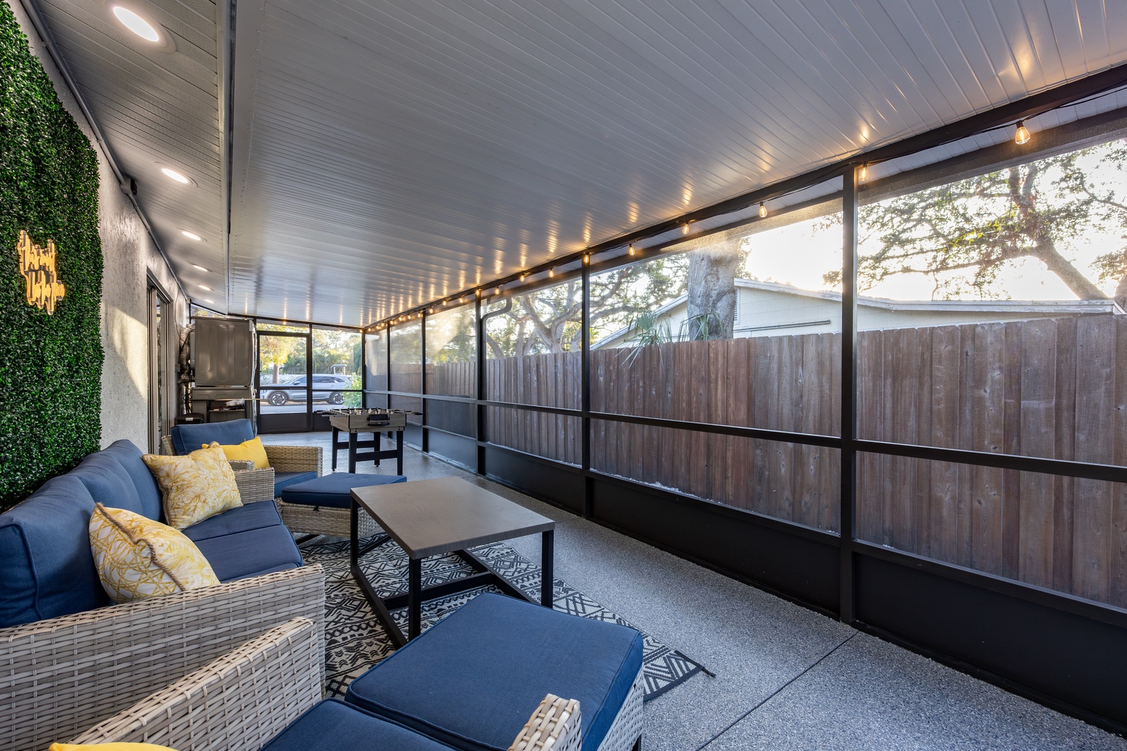 Your covered patio offers comfortable seating with stylish blue cushions and warm lighting for perfect evening relaxation outdoors.