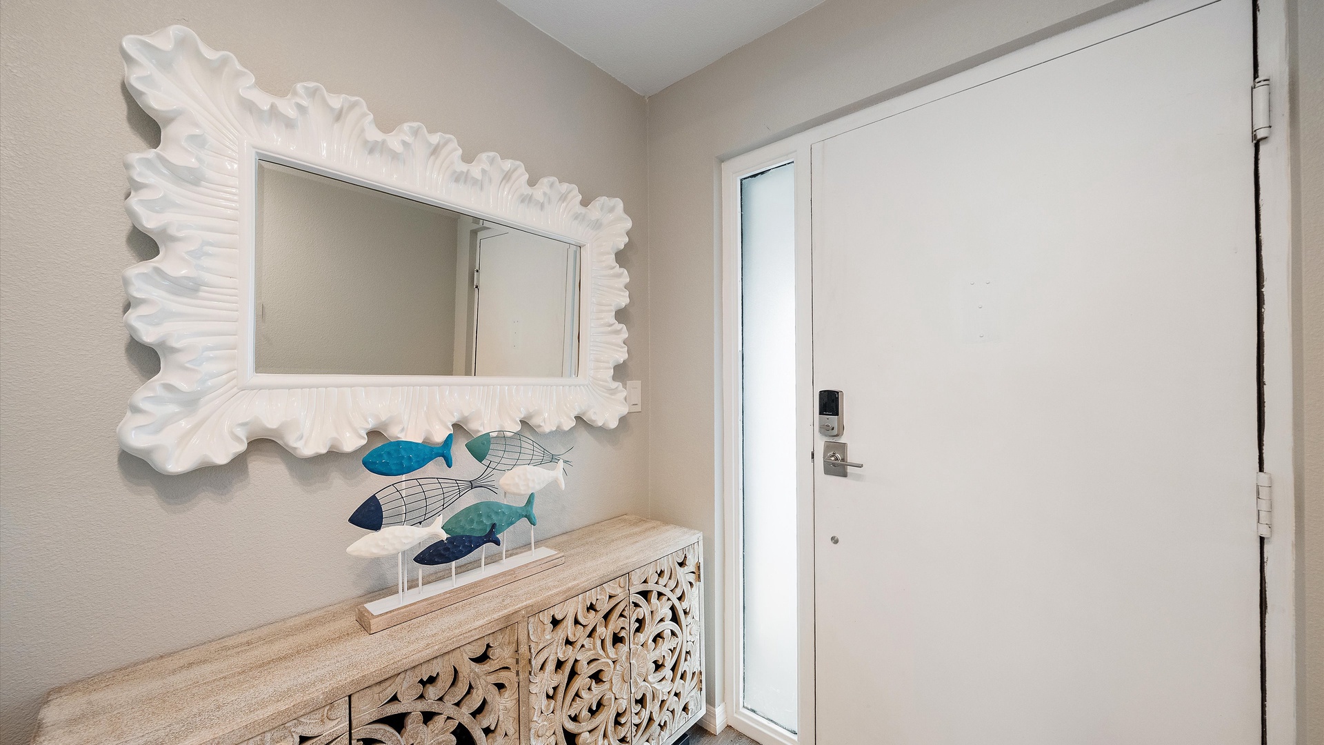Coastal charm greets you at the entrance with a decorative wave-framed mirror and cheerful wooden fish, setting a relaxed beachy tone from the moment you arrive.