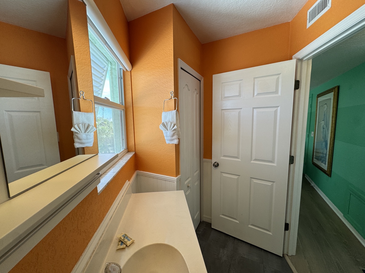 Soak in your private tub beneath a cheerful window and decorative towels, where warm orange tones create a welcoming retreat after exploring all day.