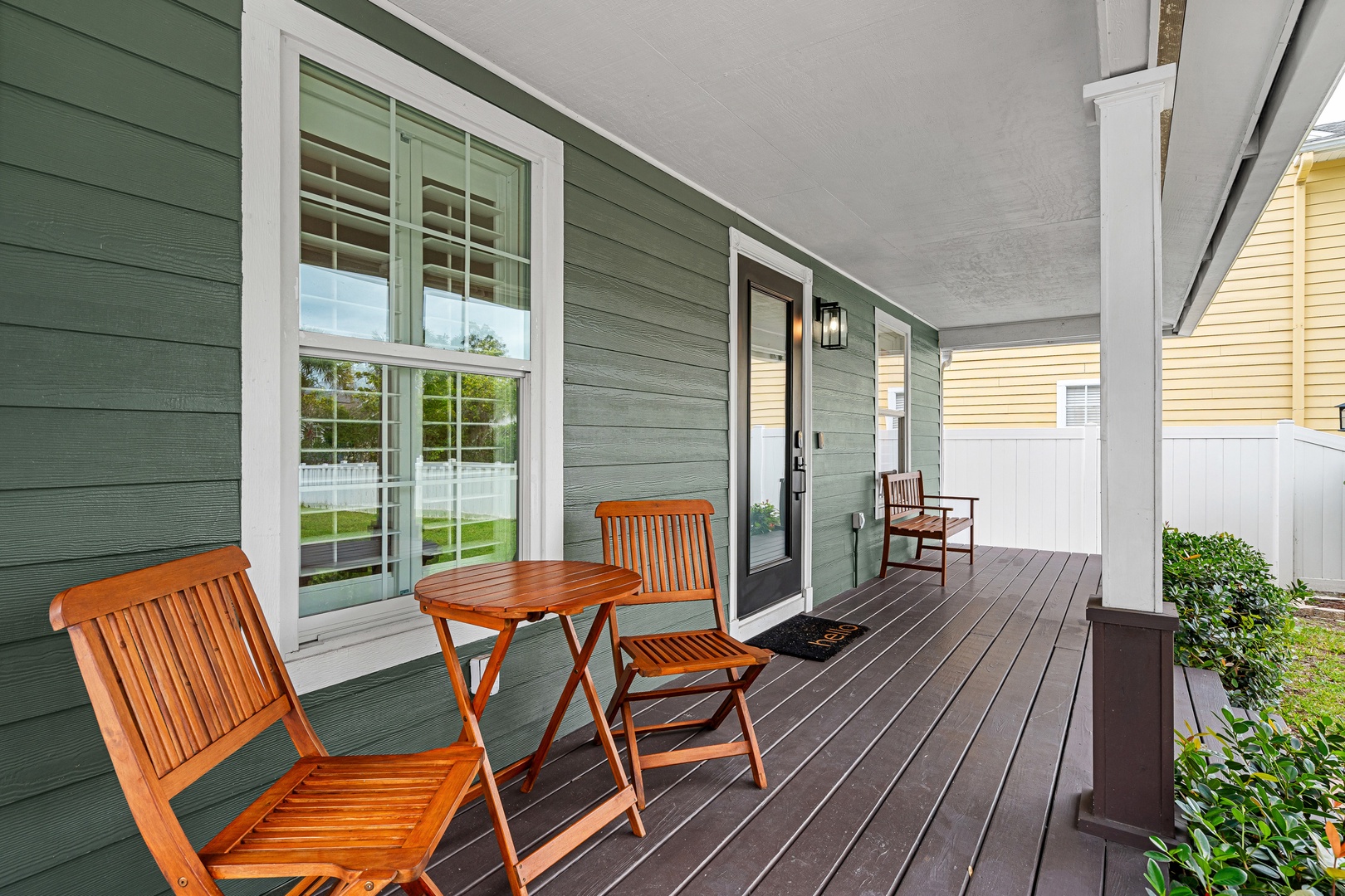 Step onto your private covered porch and settle into one of the cozy wooden chairs—your morning coffee or evening wind-down spot awaits with a peaceful neighborhood view.