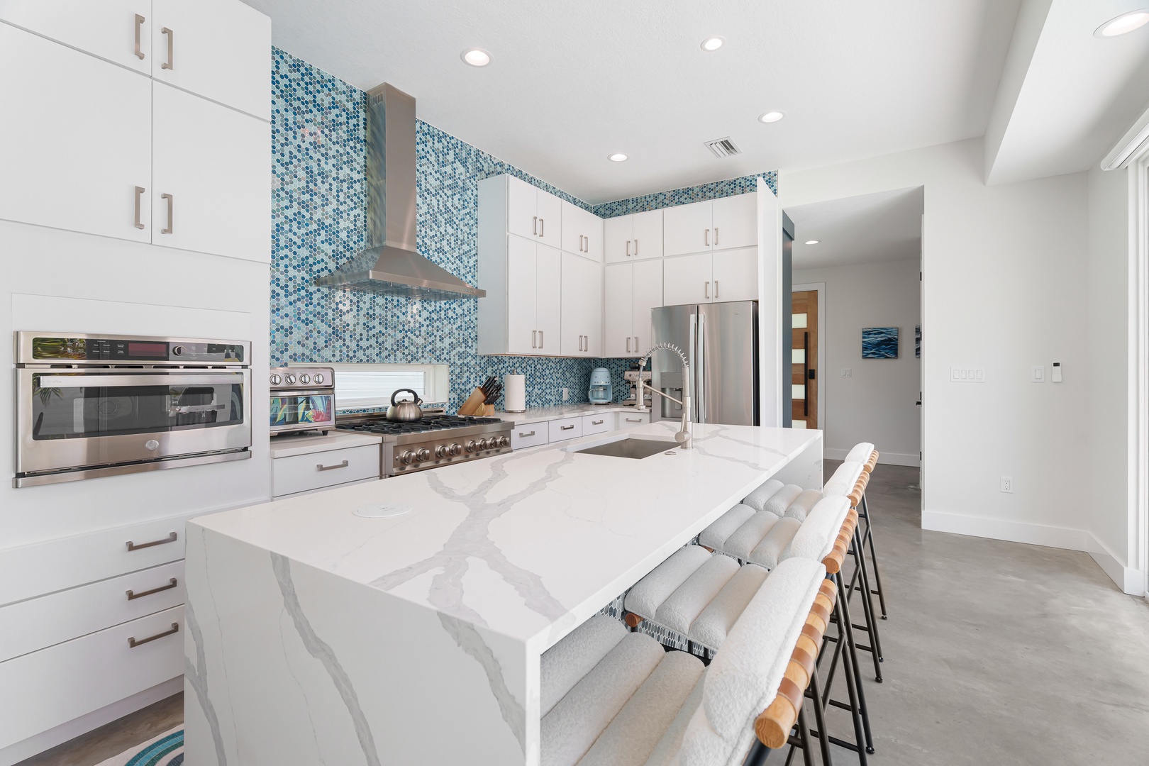 Your gourmet kitchen features stunning ocean-inspired mosaic tiles, a spacious marble island for casual meals, and top-of-the-line stainless steel appliances ready to inspire culinary adventures.