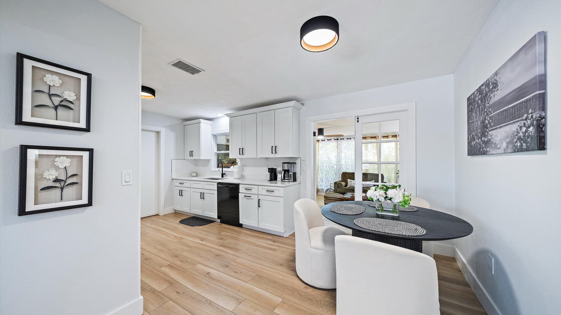 Gather around the sleek dining table in this bright, open kitchen where warm wood floors and modern fixtures create an inviting space for your morning coffee or evening meals together.