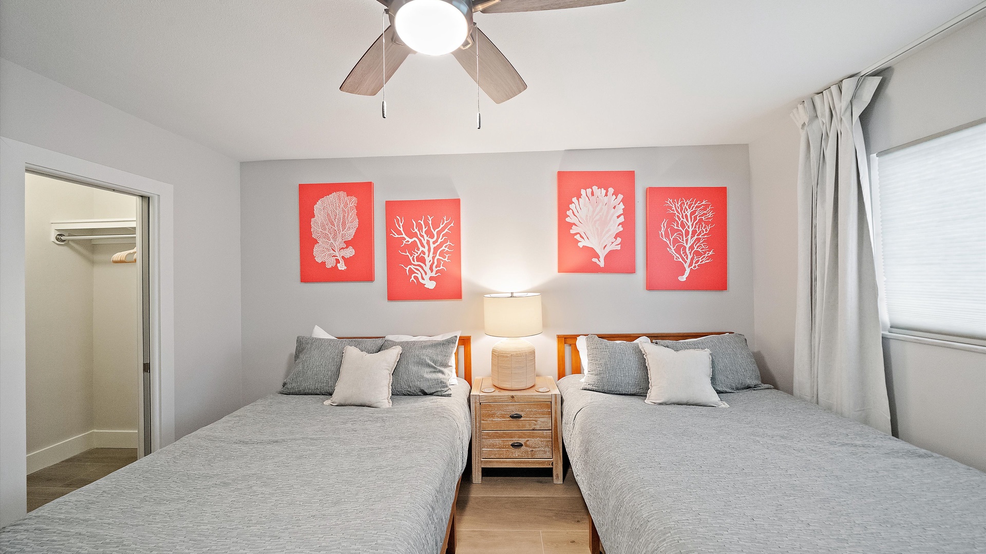 Drift off in your bright twin bedroom featuring coastal coral art and gentle ceiling fan breezes for perfect sleeping comfort.